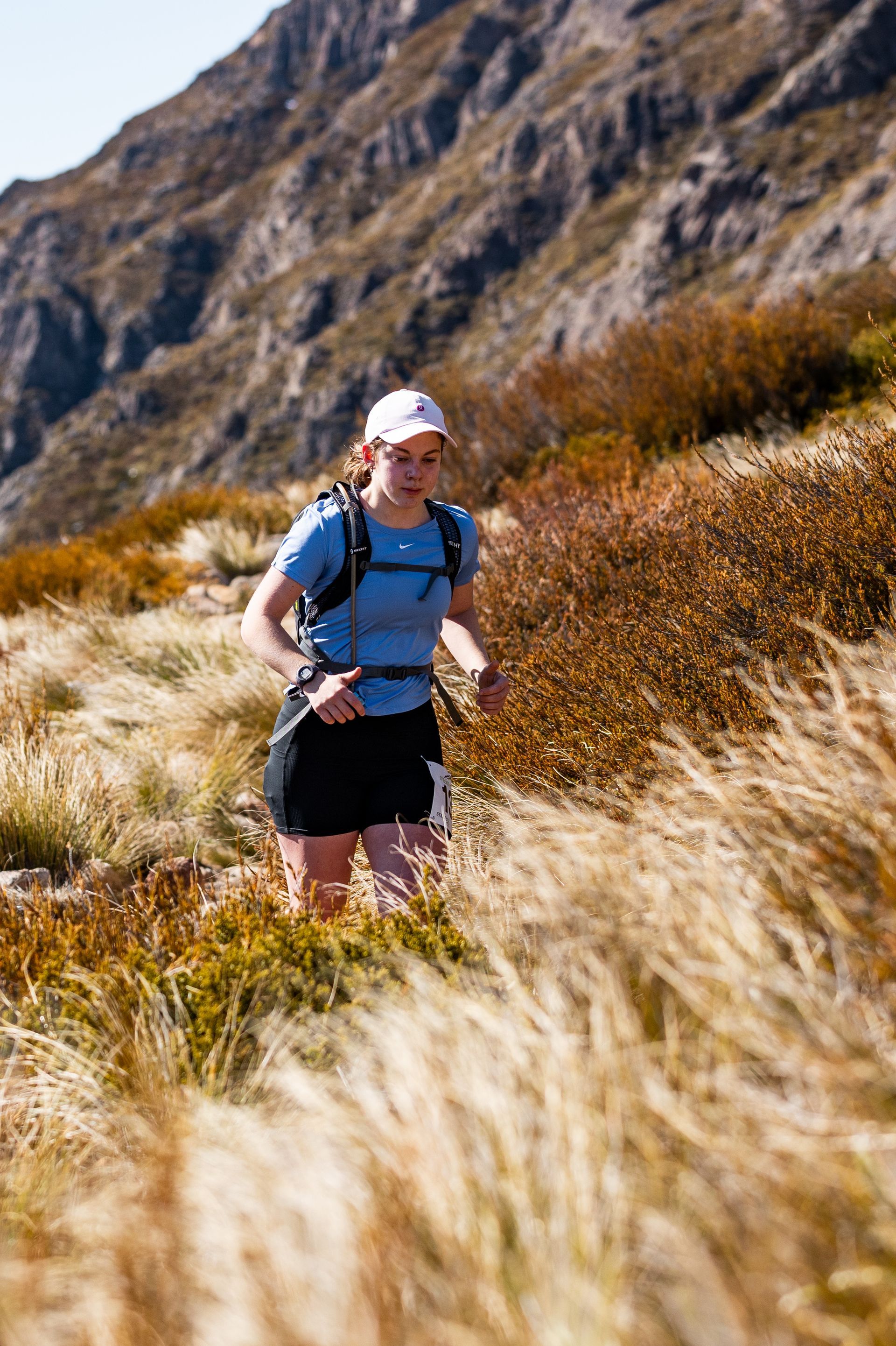 A woman is running on a trail in the mountains.