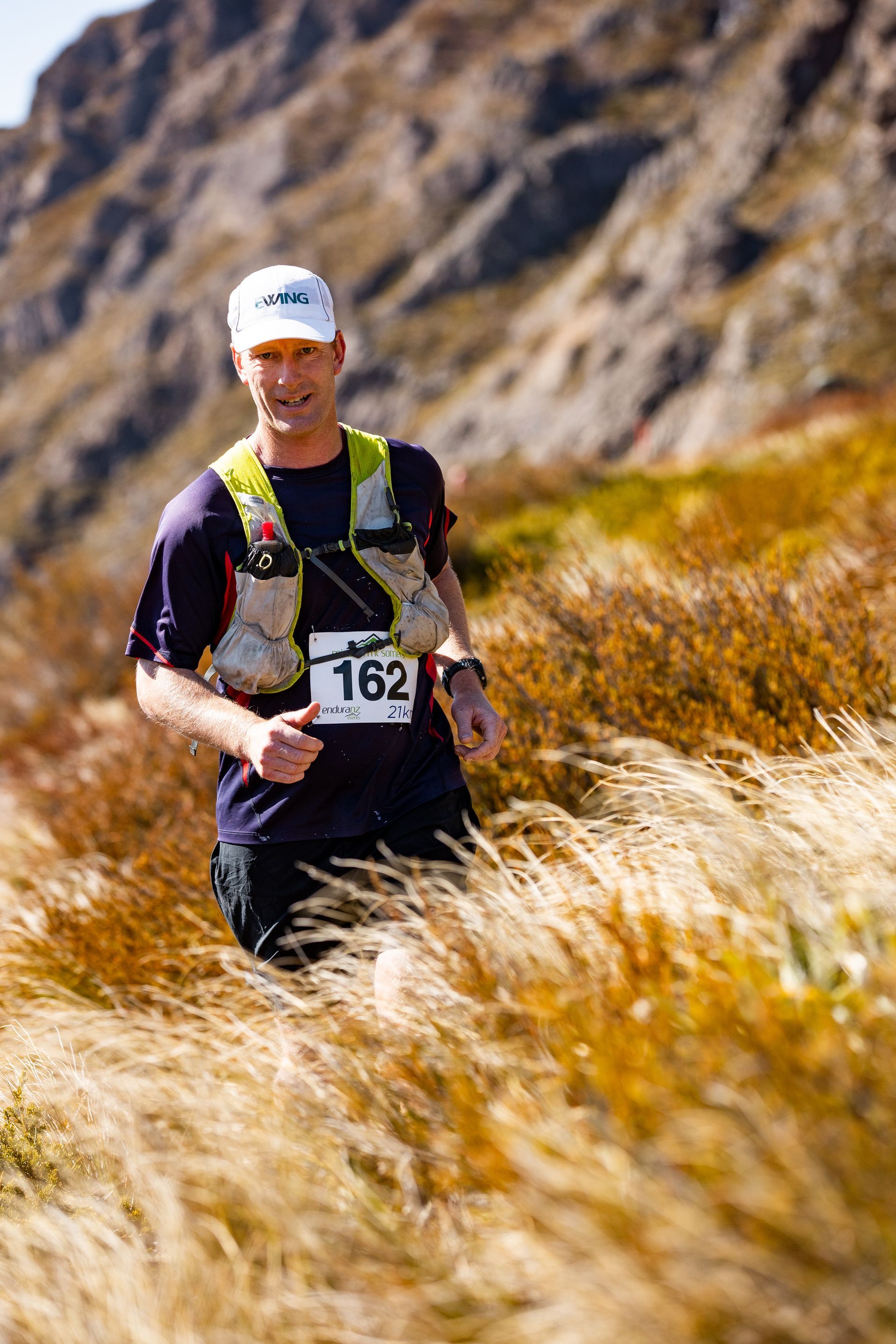 A man is running through a field of tall grass.