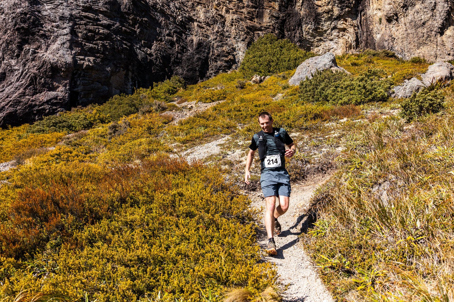 A man is running on a trail in the mountains.