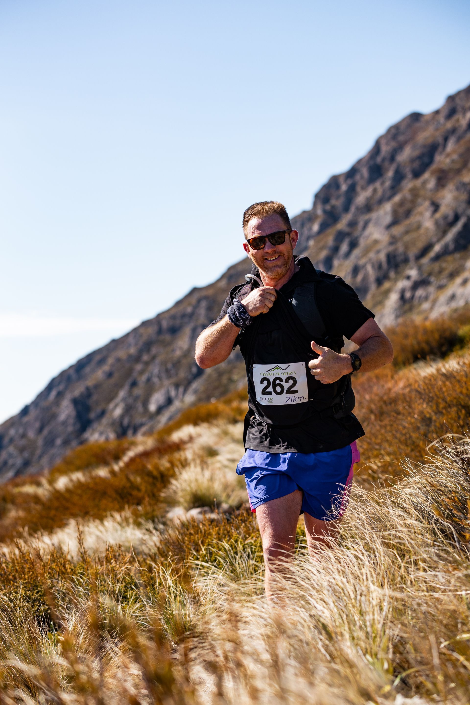 A man is running on a trail in the mountains.