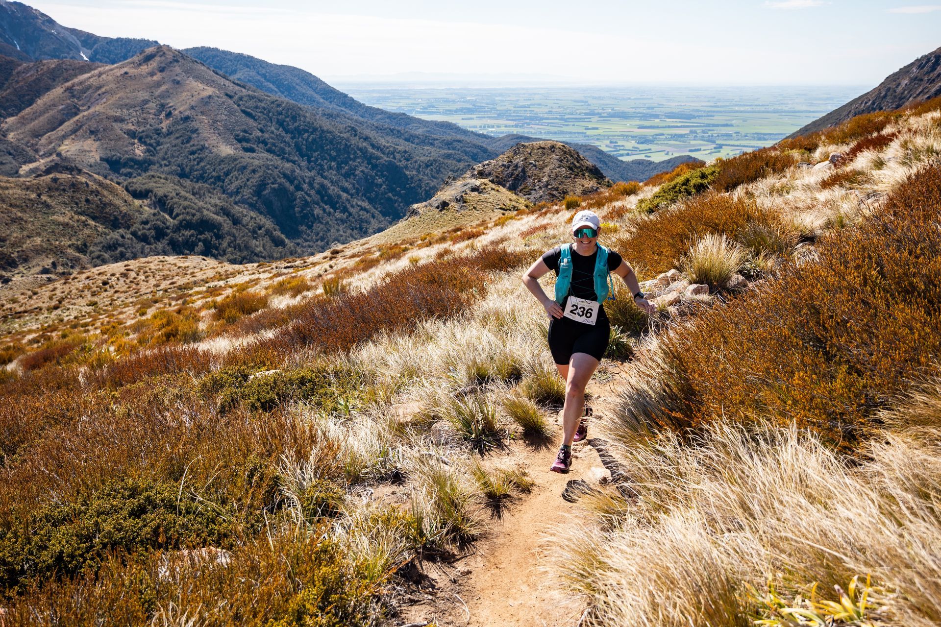A woman is running on a trail in the mountains.