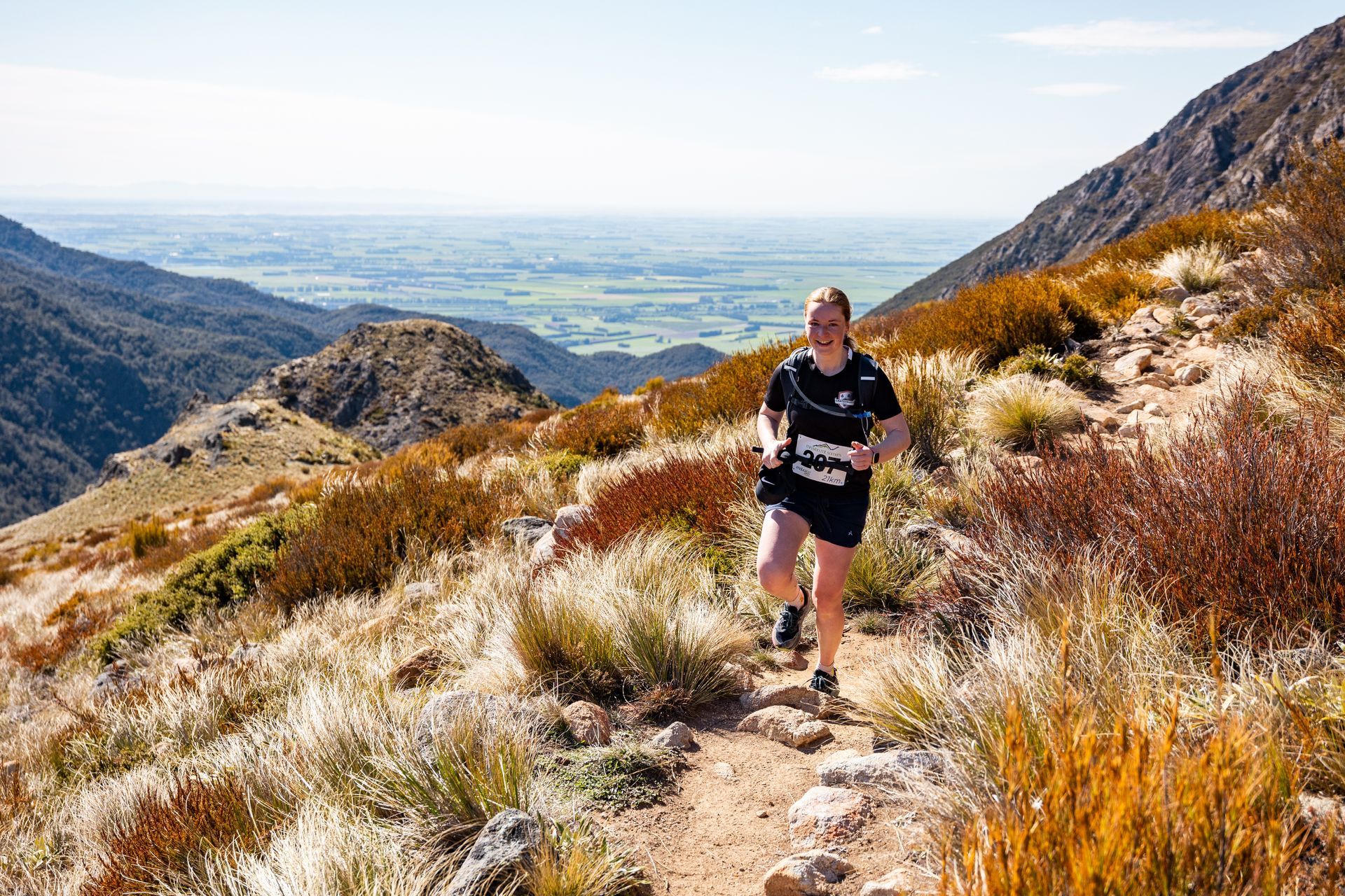 A woman is running on a trail in the mountains.