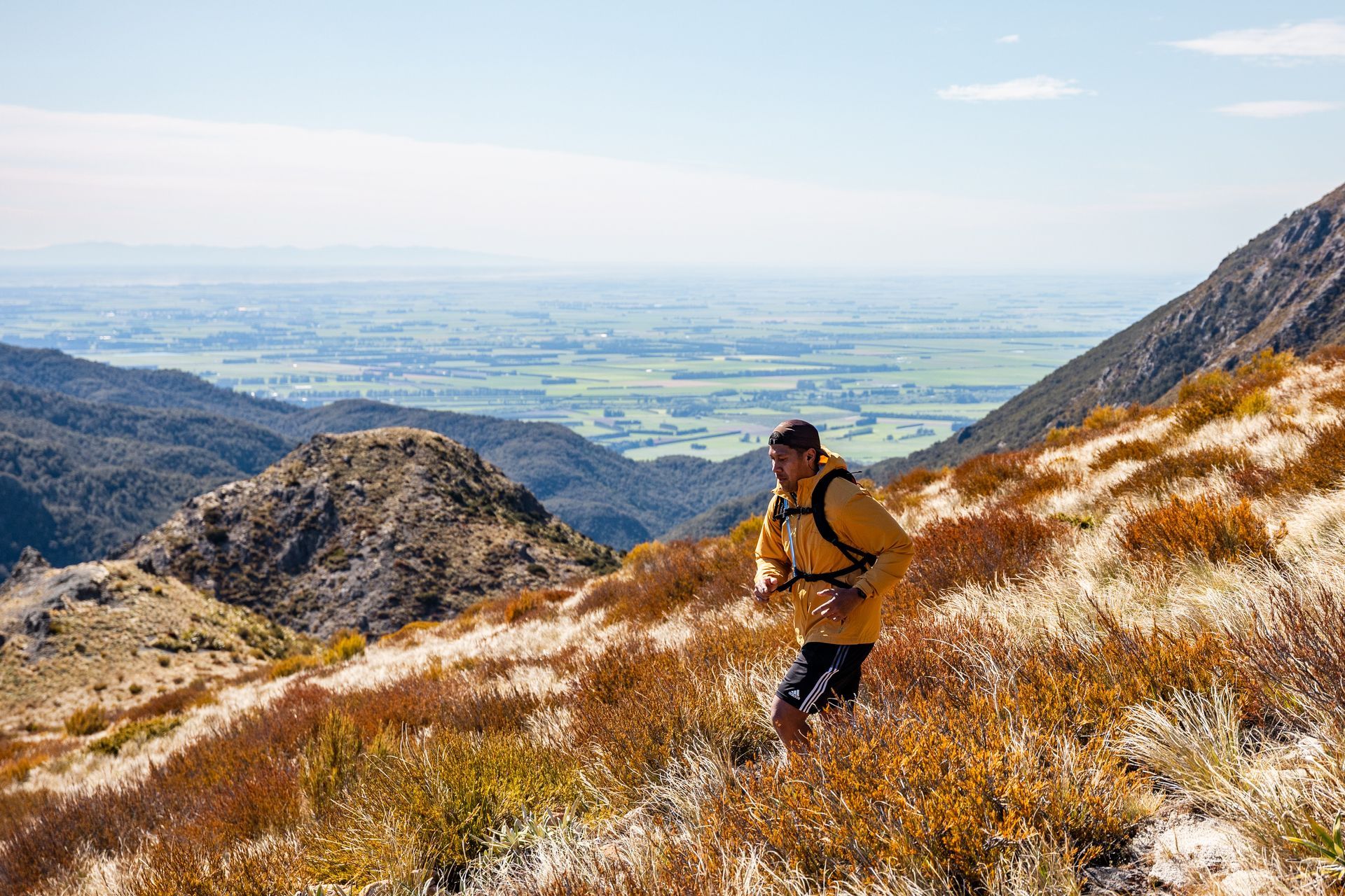 A man is running up a hill in the mountains.