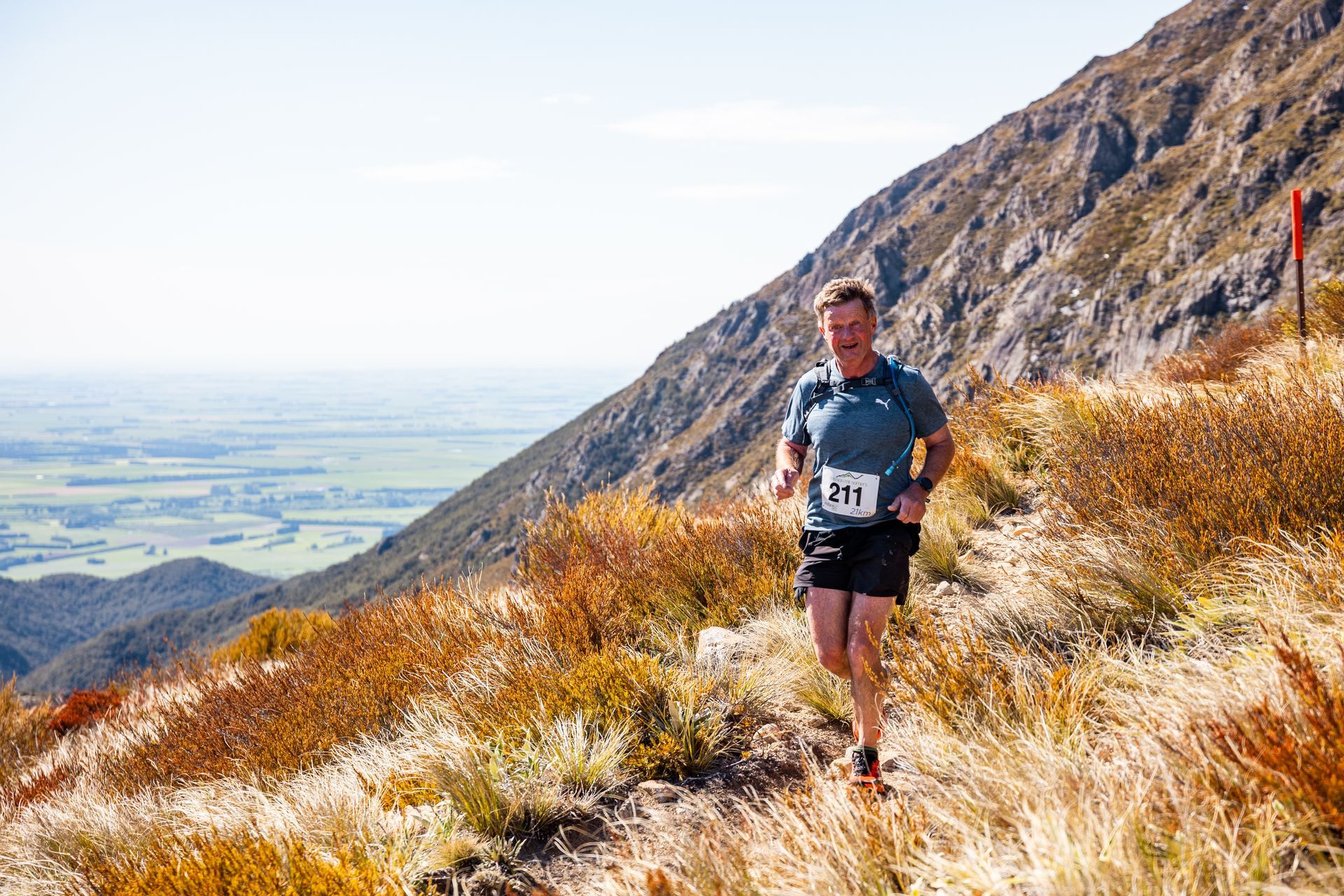 A man is running on a trail on top of a mountain.