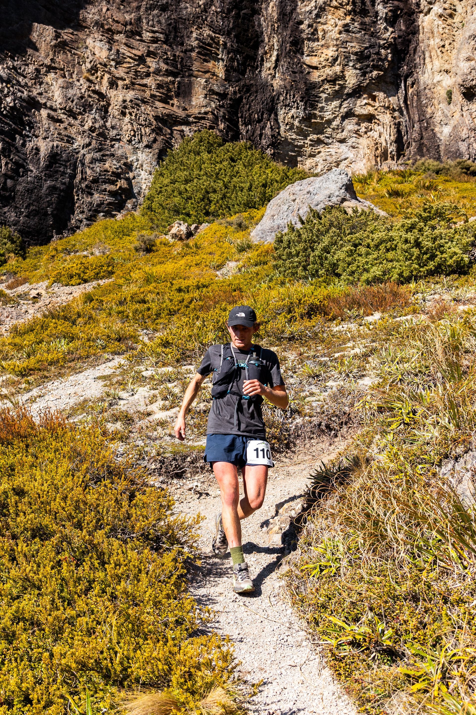 A man is running down a dirt path in the mountains.