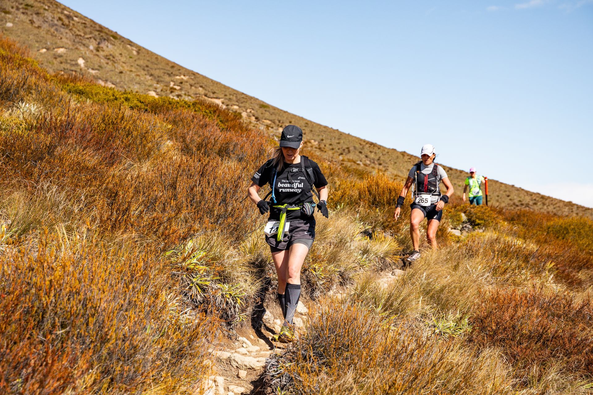 A group of people are running up a hill on a trail.