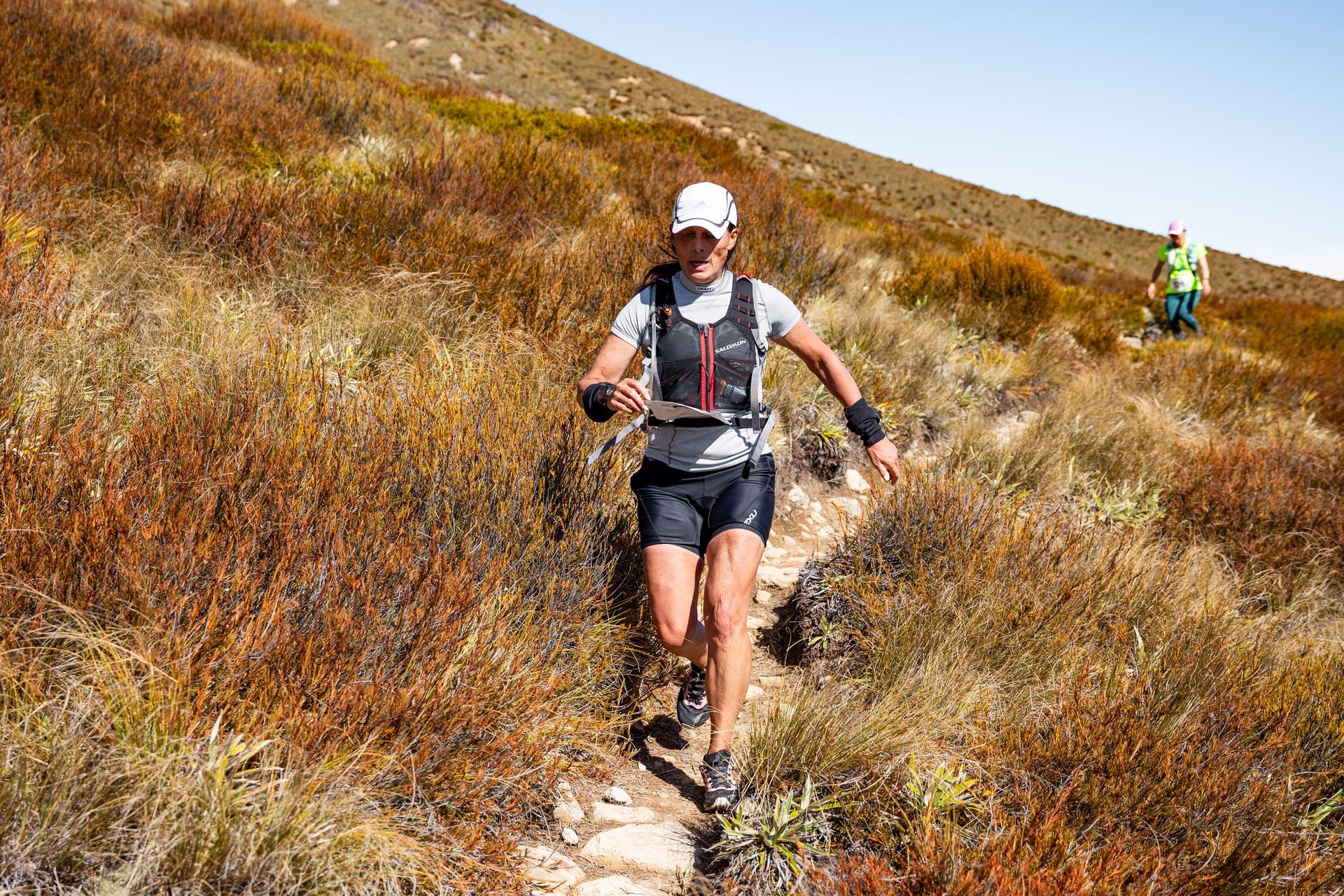 A woman is running on a trail in the mountains.