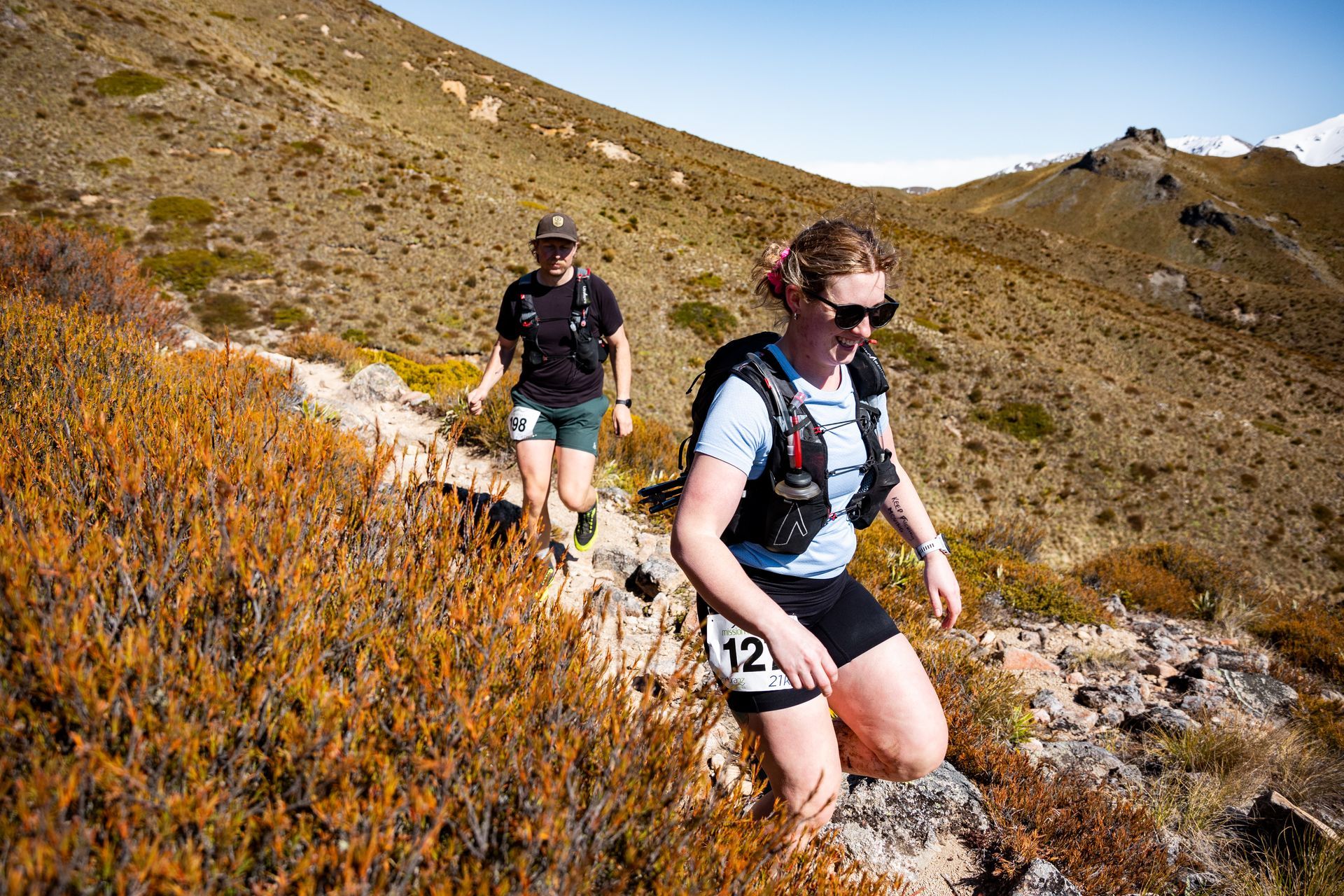 A man and a woman are hiking up a hill.