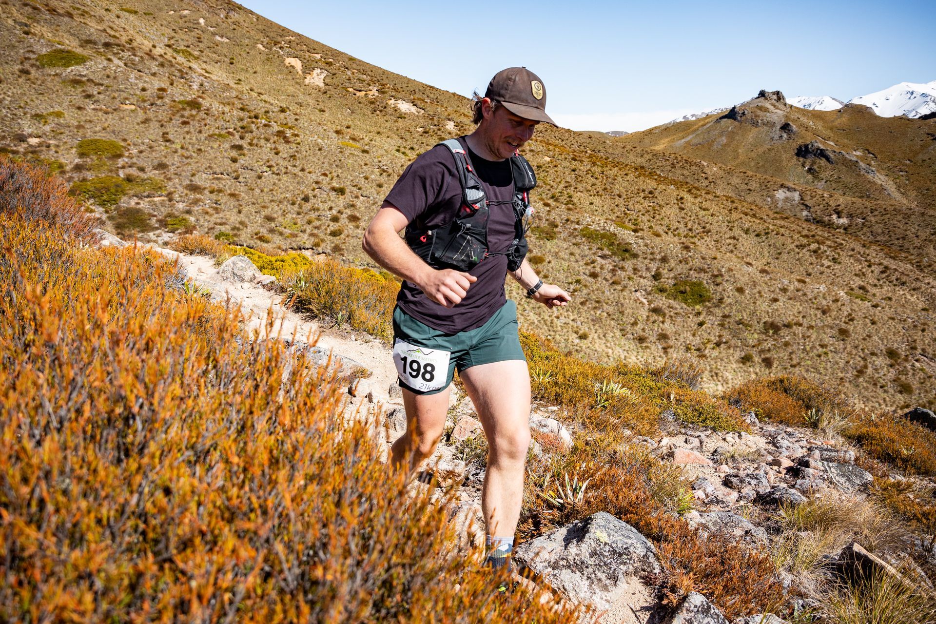 A man is running on a trail in the mountains.