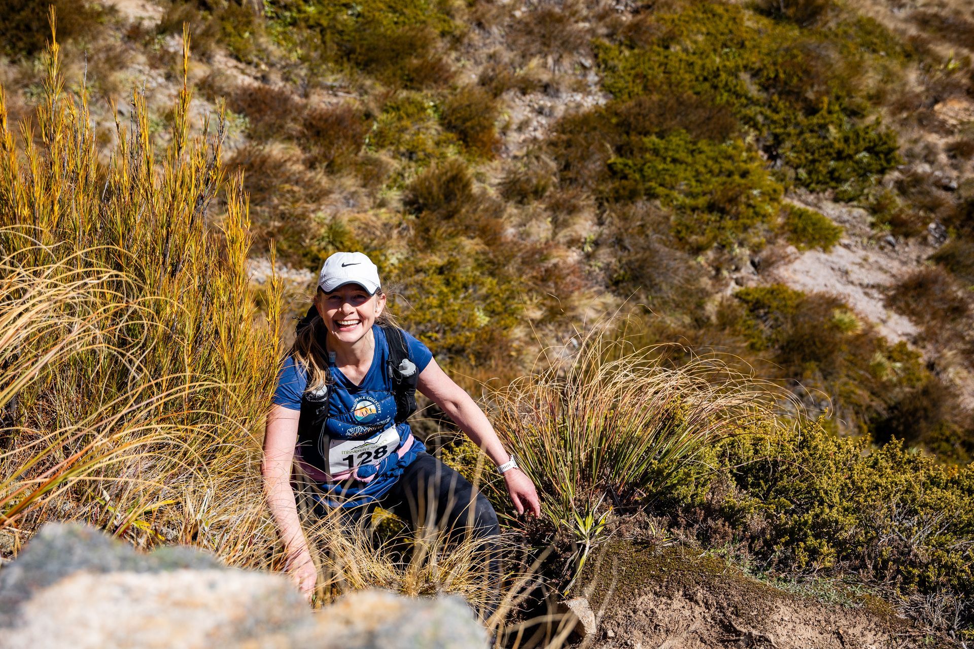 A woman is hiking up a hill in the mountains.