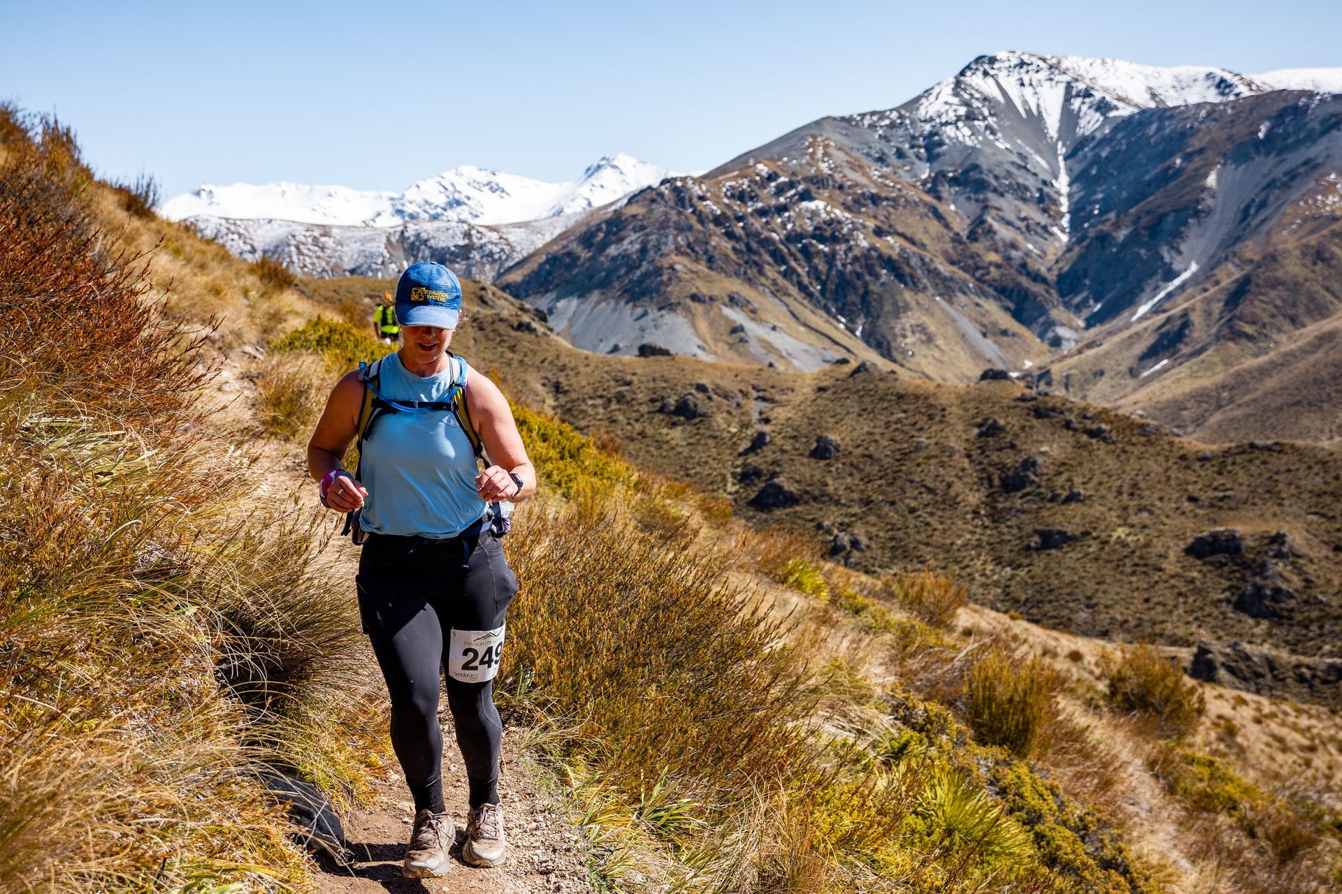 A woman is running on a trail in the mountains.