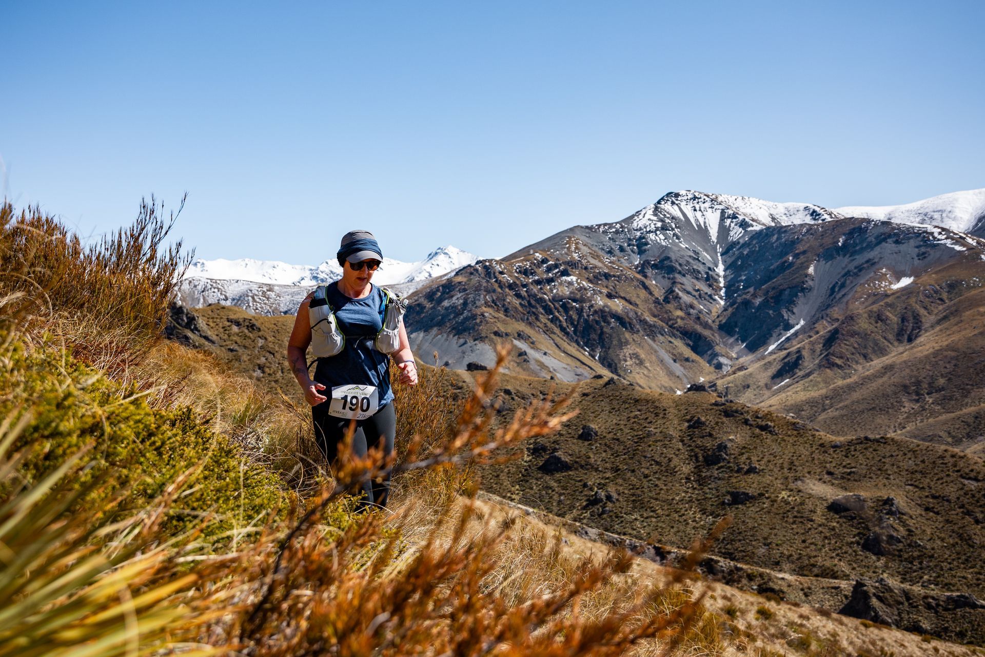 A man is running on a trail in the mountains.