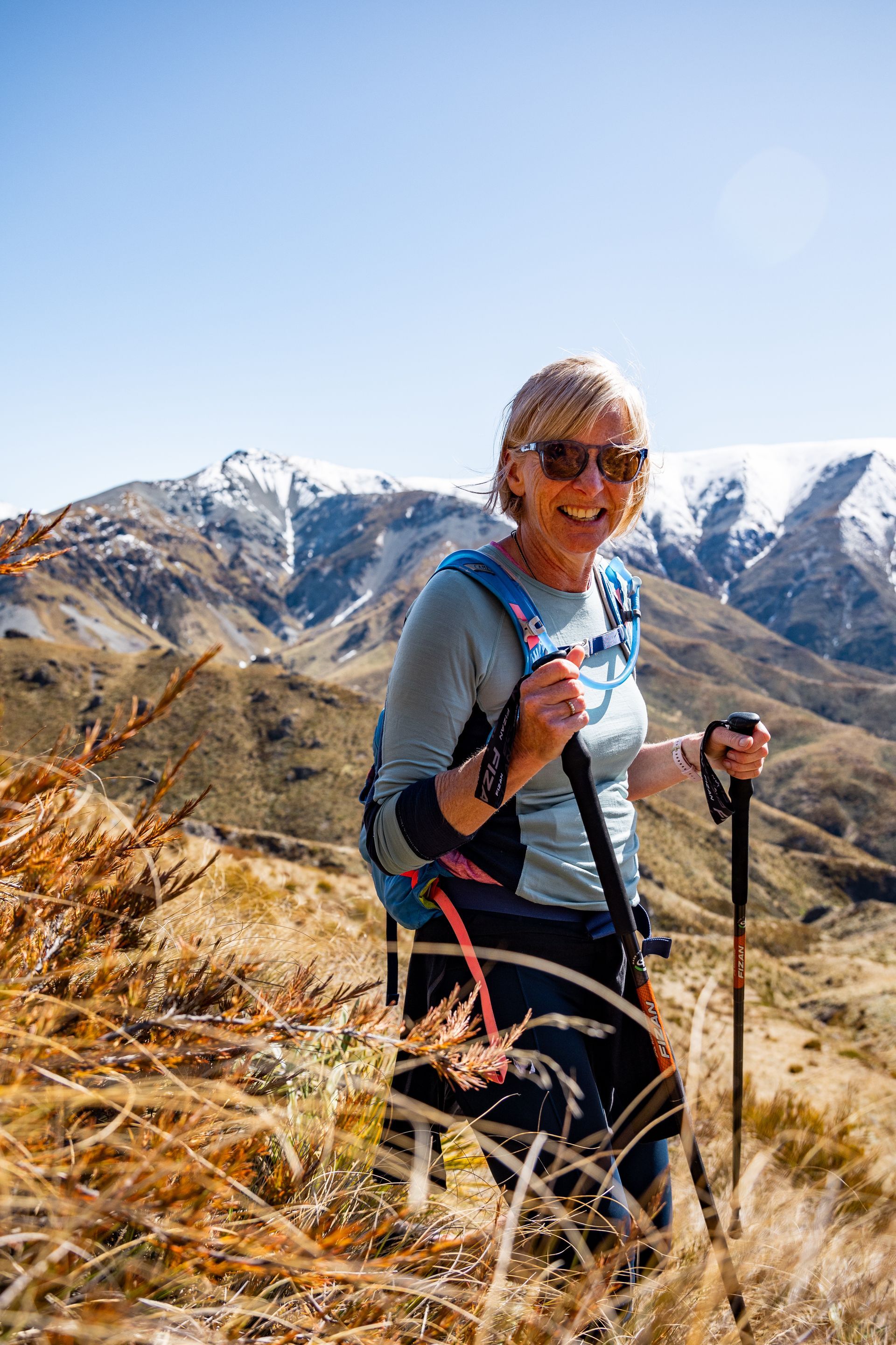 A woman is hiking in the mountains with a backpack and walking poles.