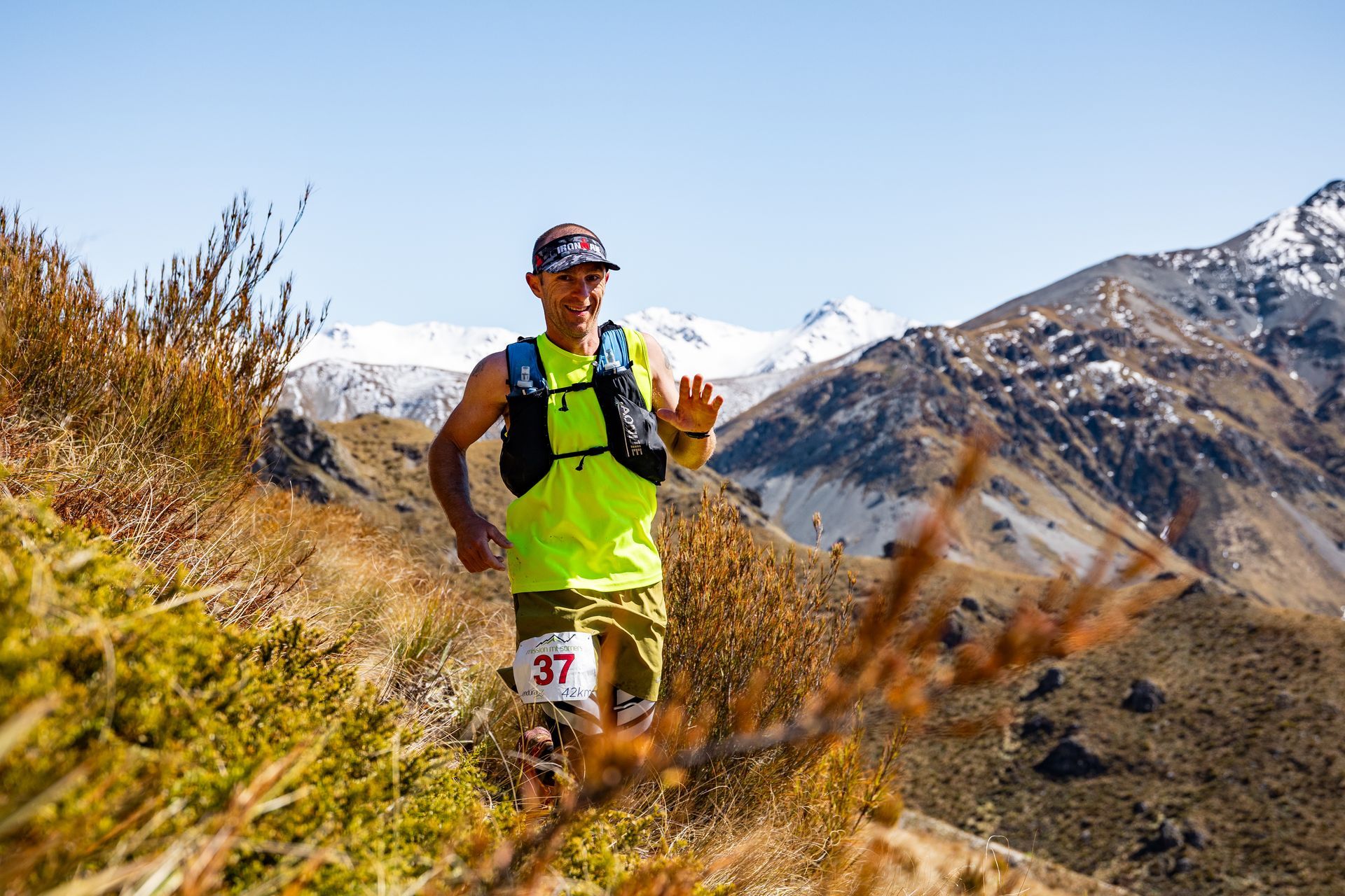 A man is running on a trail in the mountains.