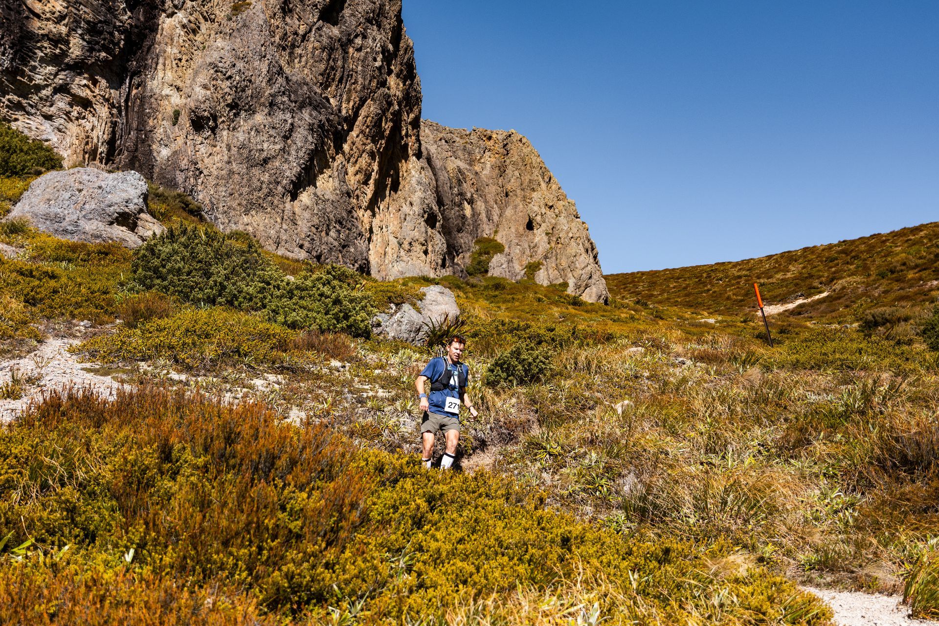 A man is walking on a trail in the mountains.