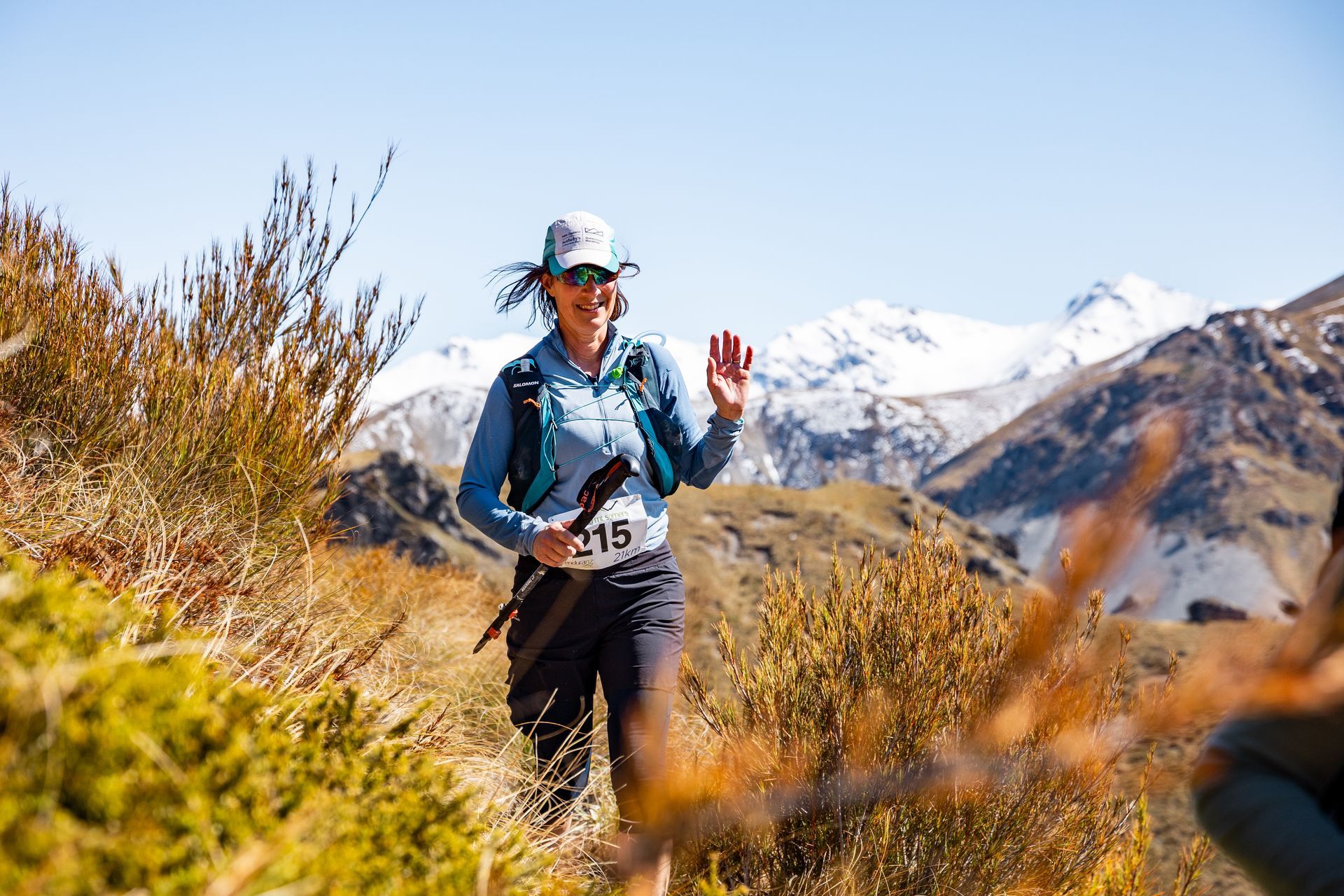 A woman is walking on a trail in the mountains.