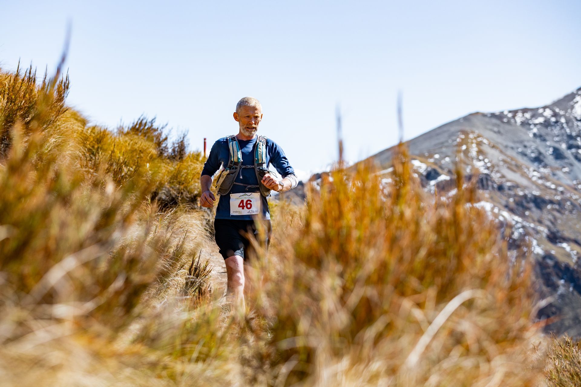 A man is running on a trail in the mountains.