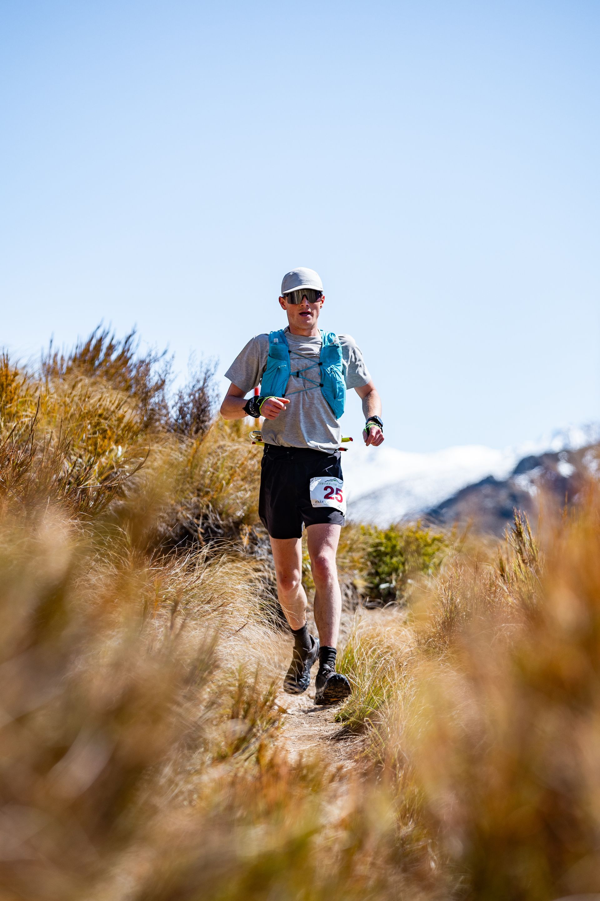 A man is running on a trail in the mountains.