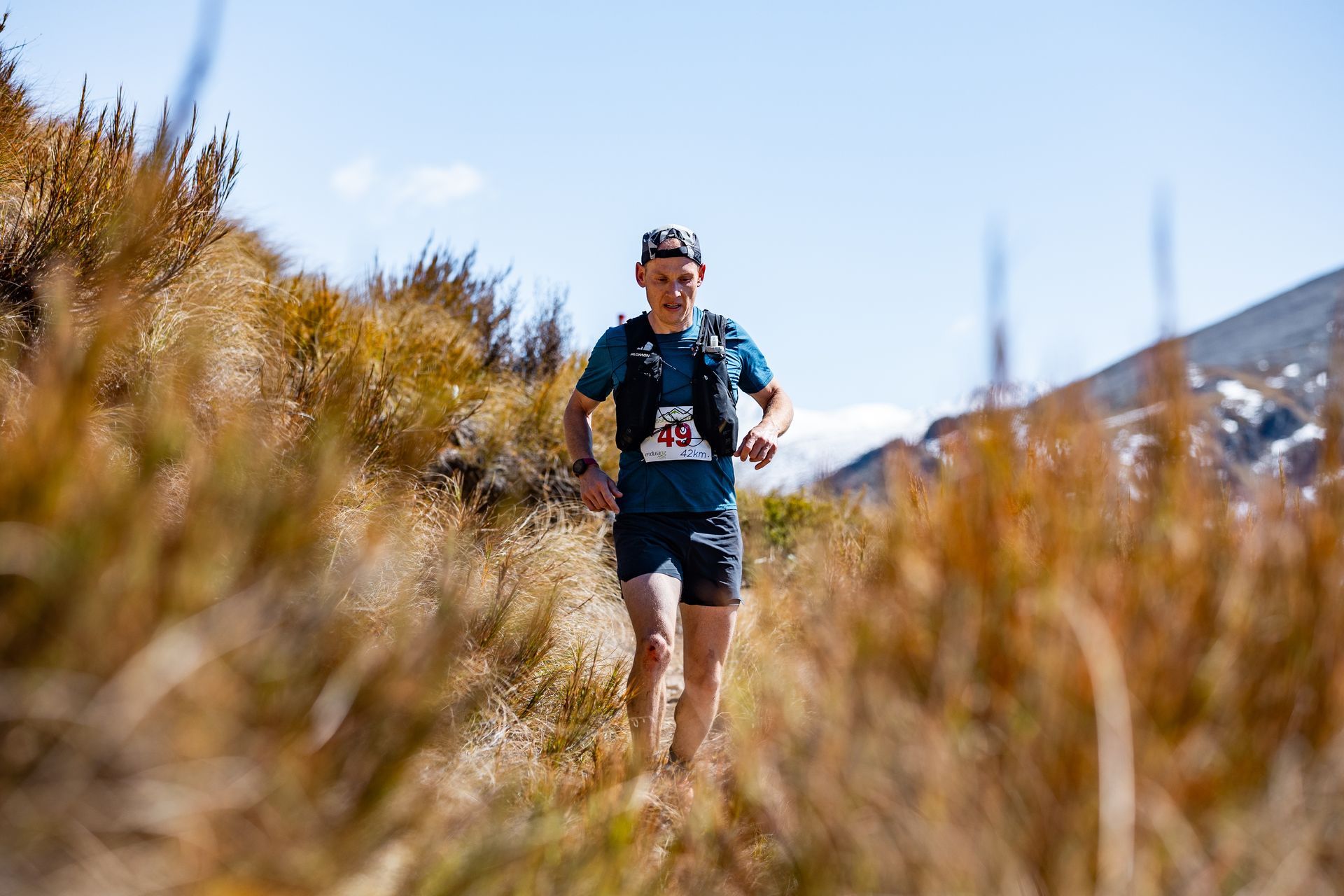A man is running on a trail in the mountains.