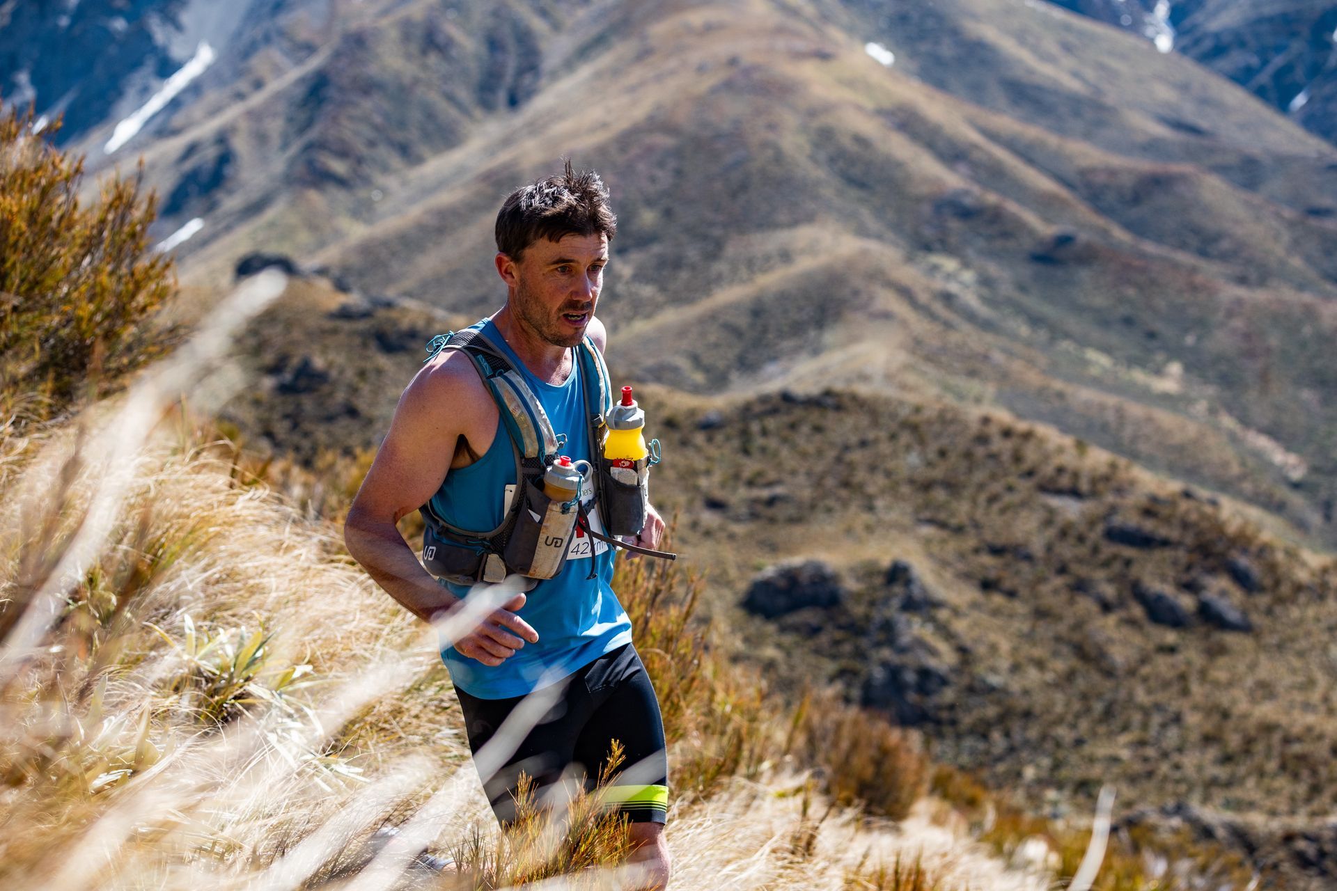 A man is running on a trail in the mountains.