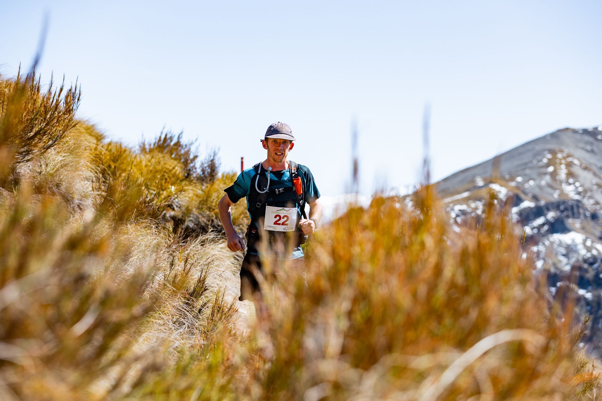 A man is running on a trail in the mountains.