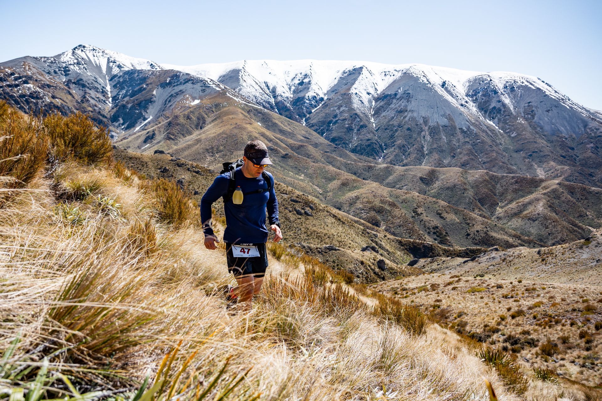 A man is running on a trail in the mountains.