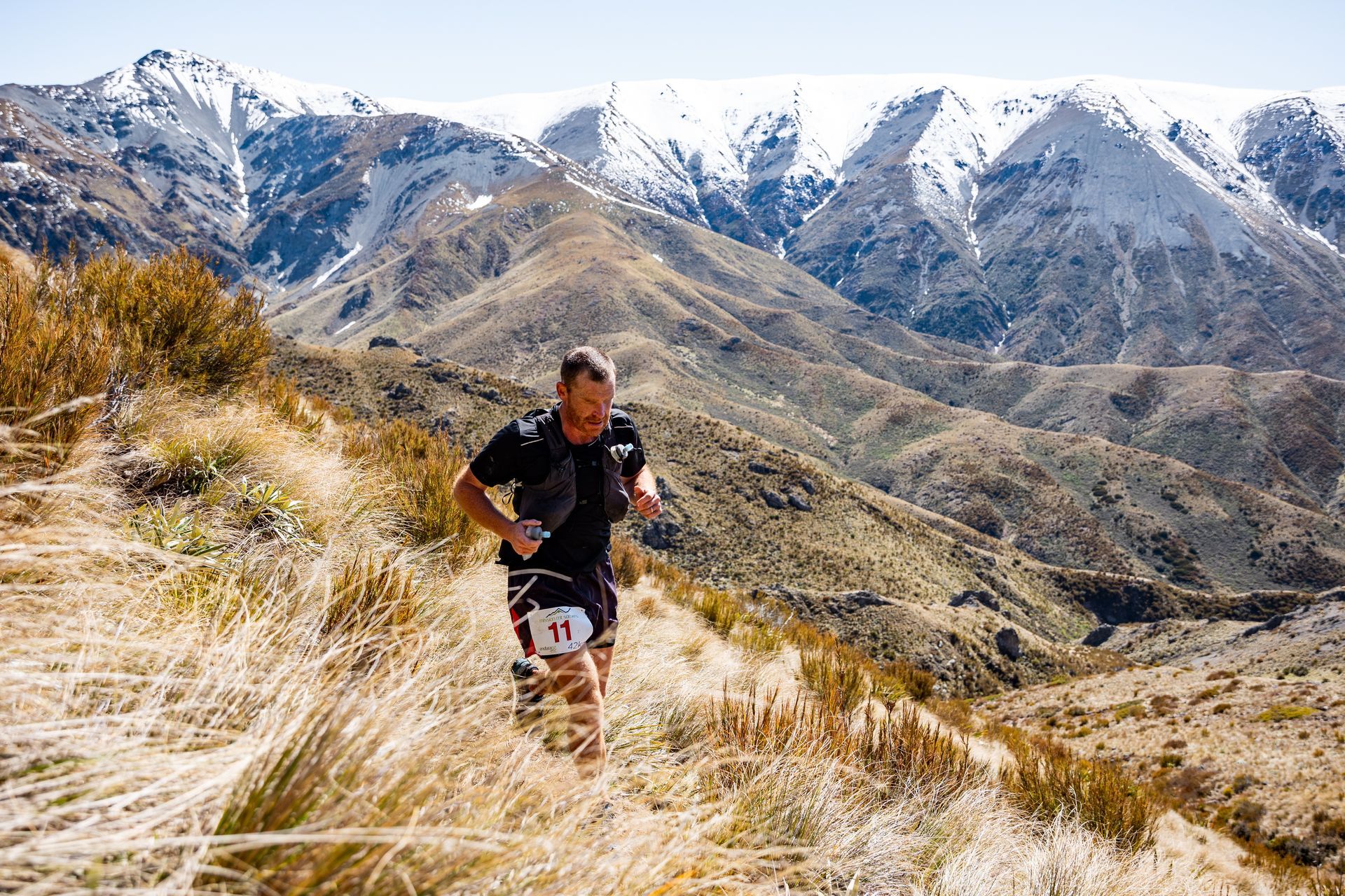 A man is running on a trail in the mountains.