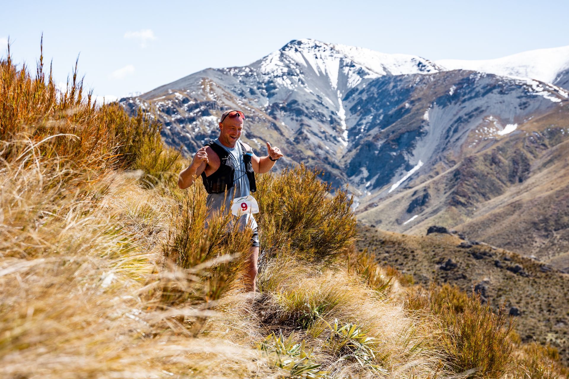 A man is running on a trail in the mountains.