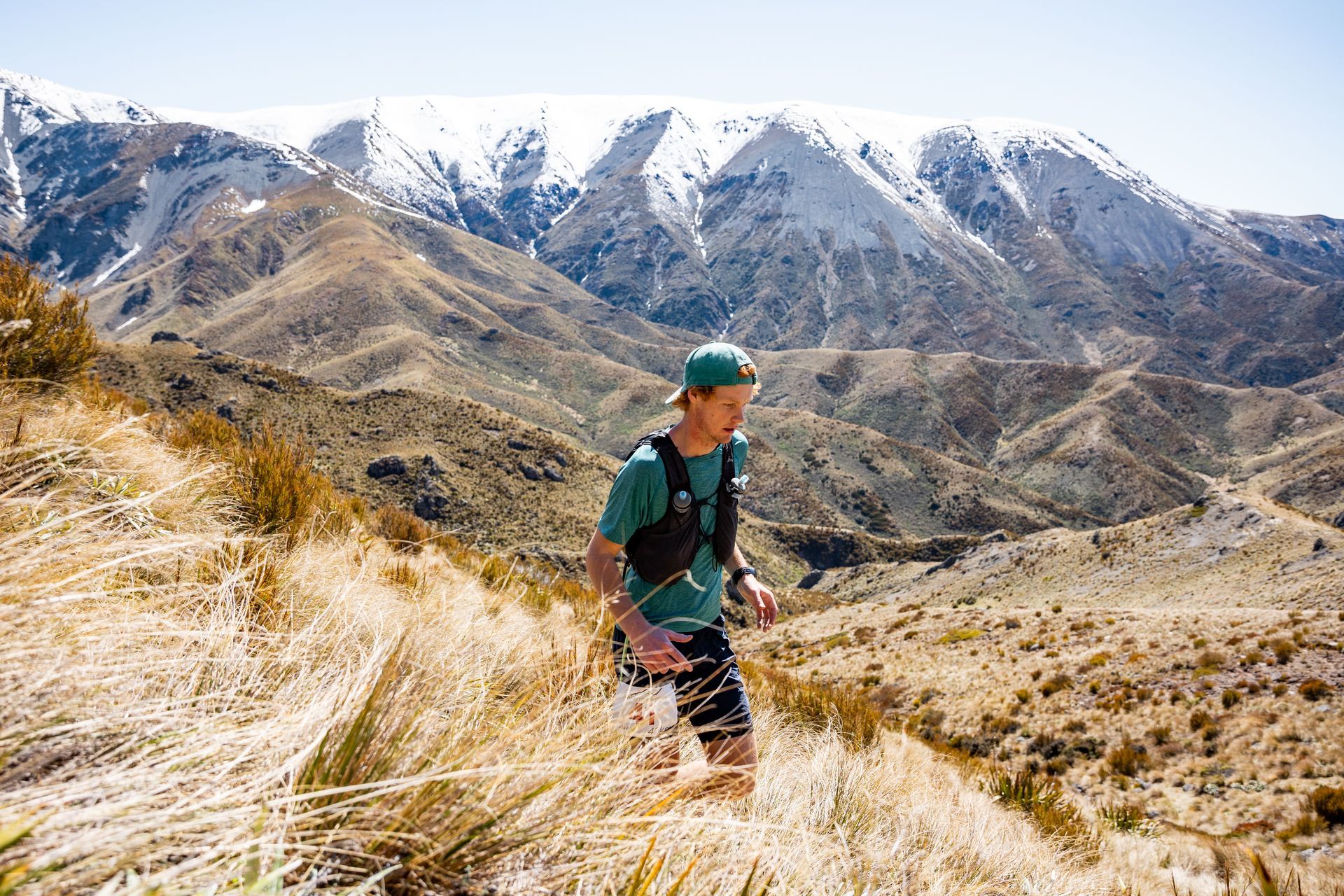 A man is running on a trail in the mountains.