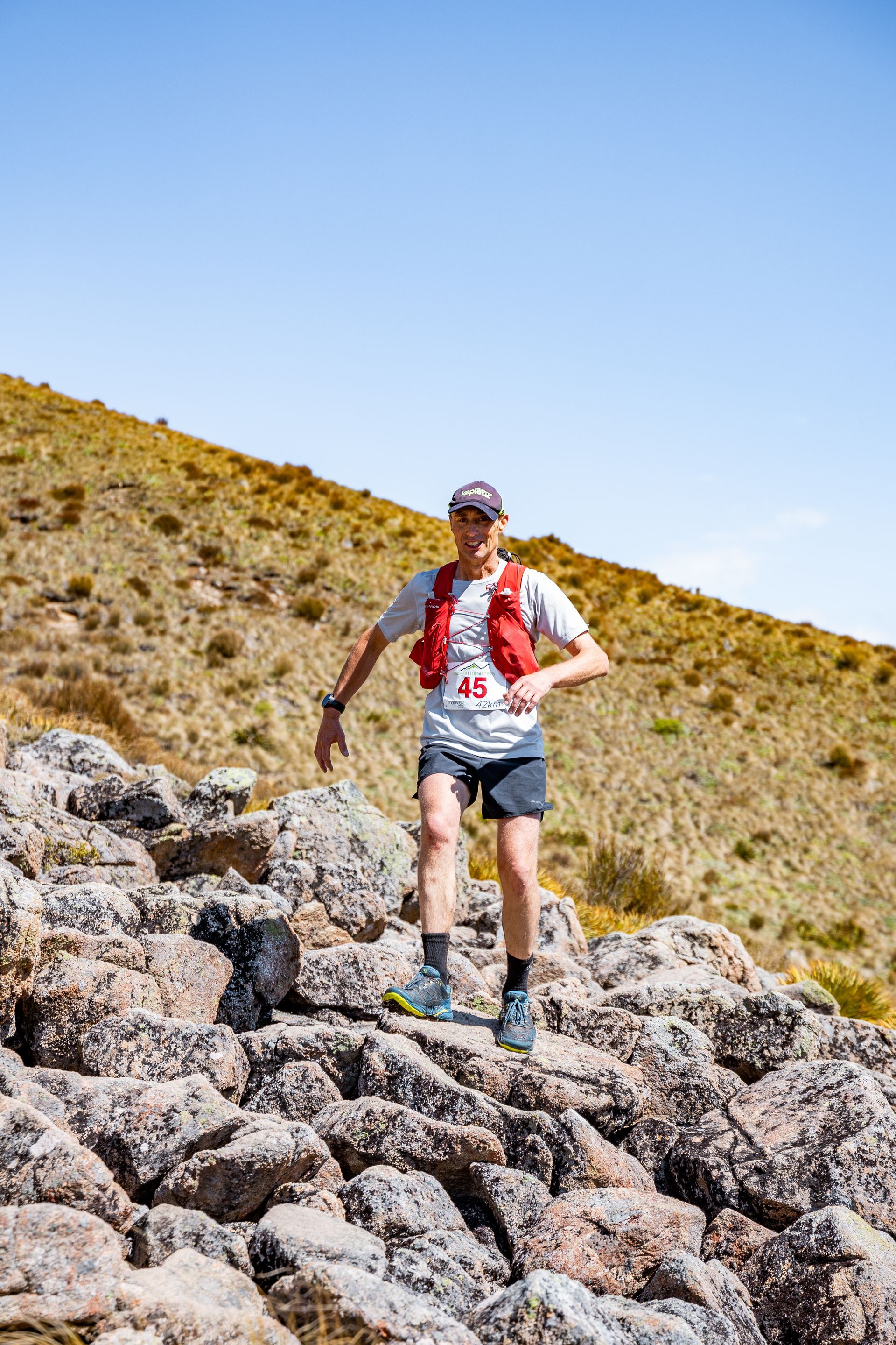 A man is standing on a rocky hillside.