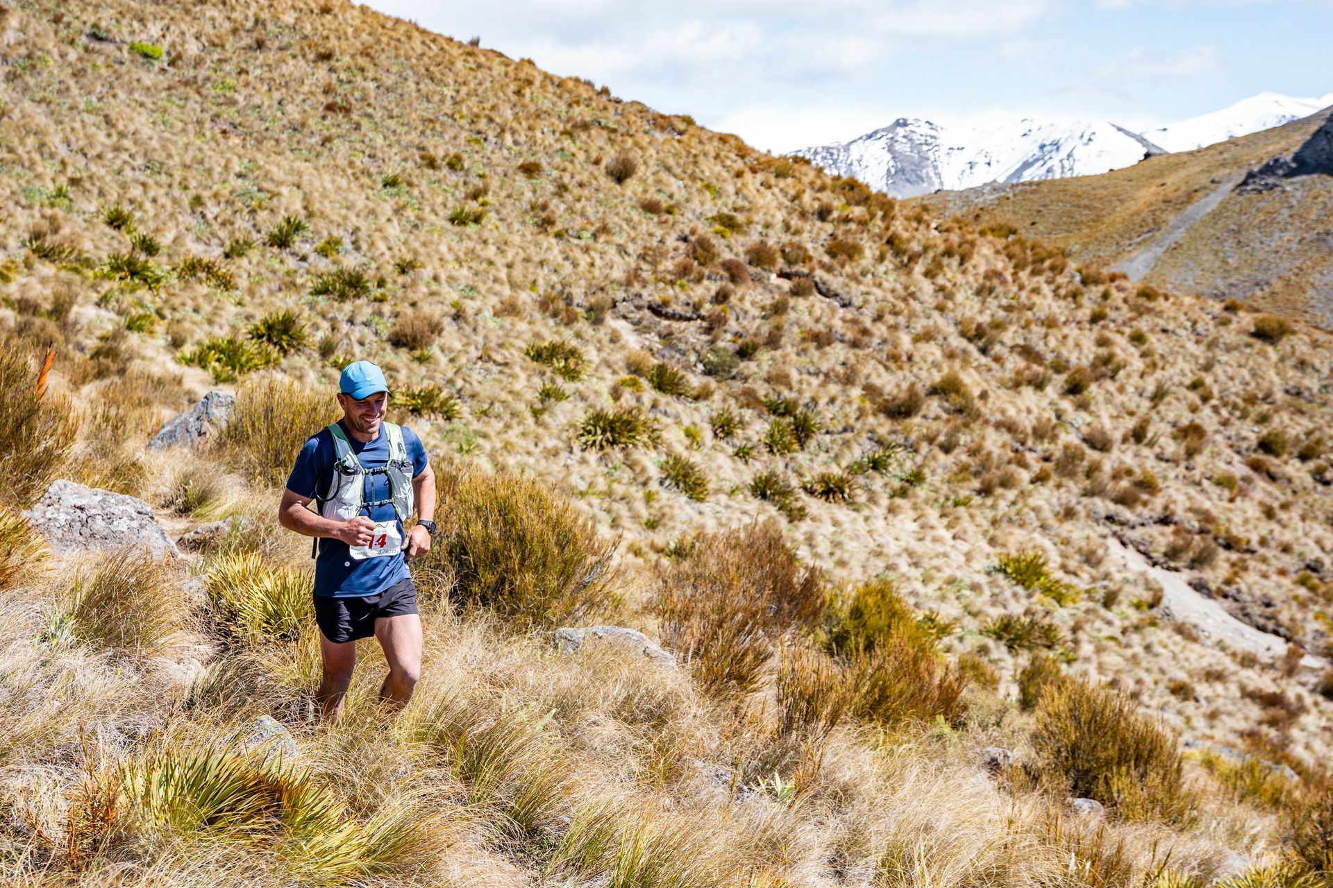 A man is running on a trail in the mountains.