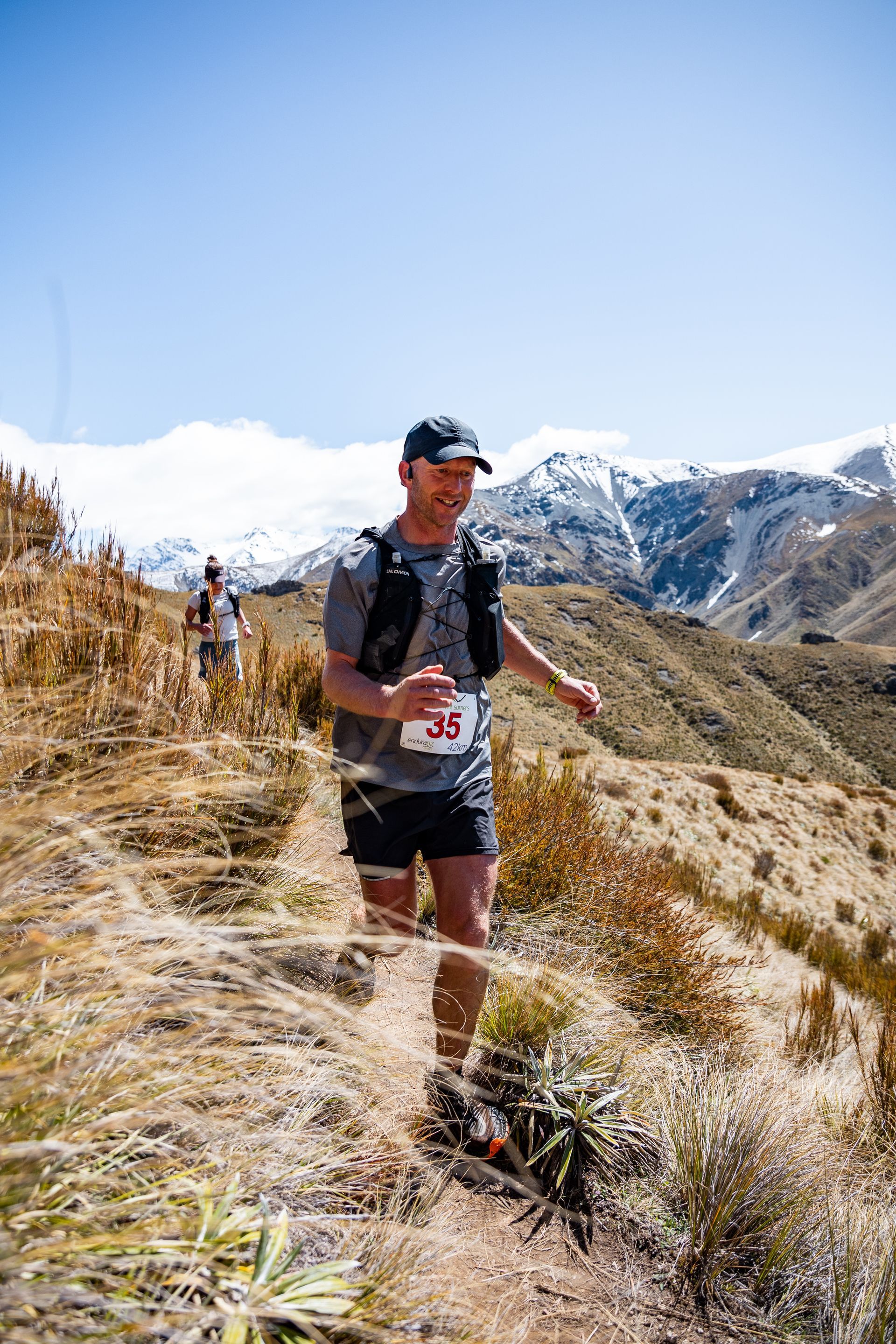 A man is running on a trail in the mountains.