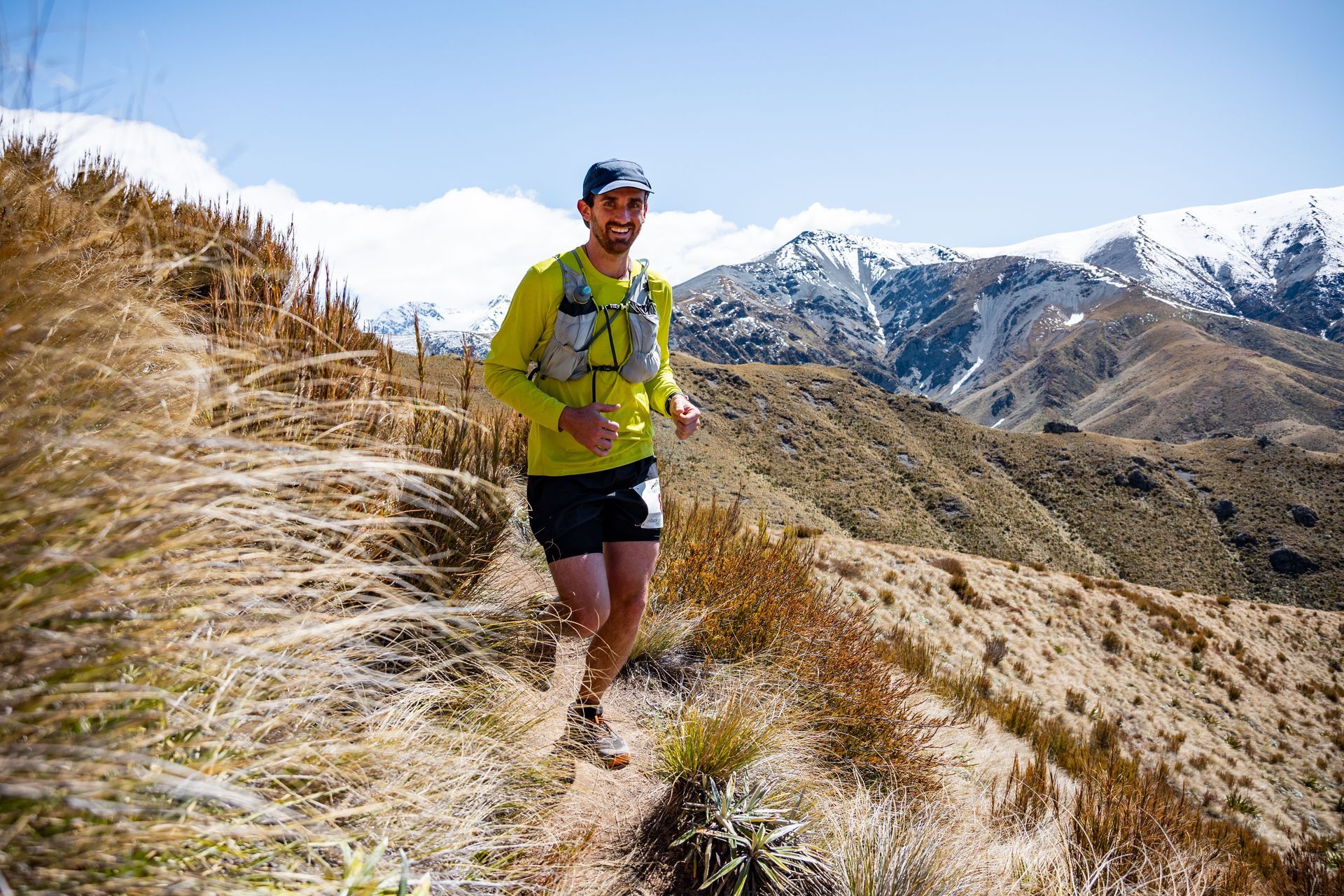 A man is running on a trail in the mountains.