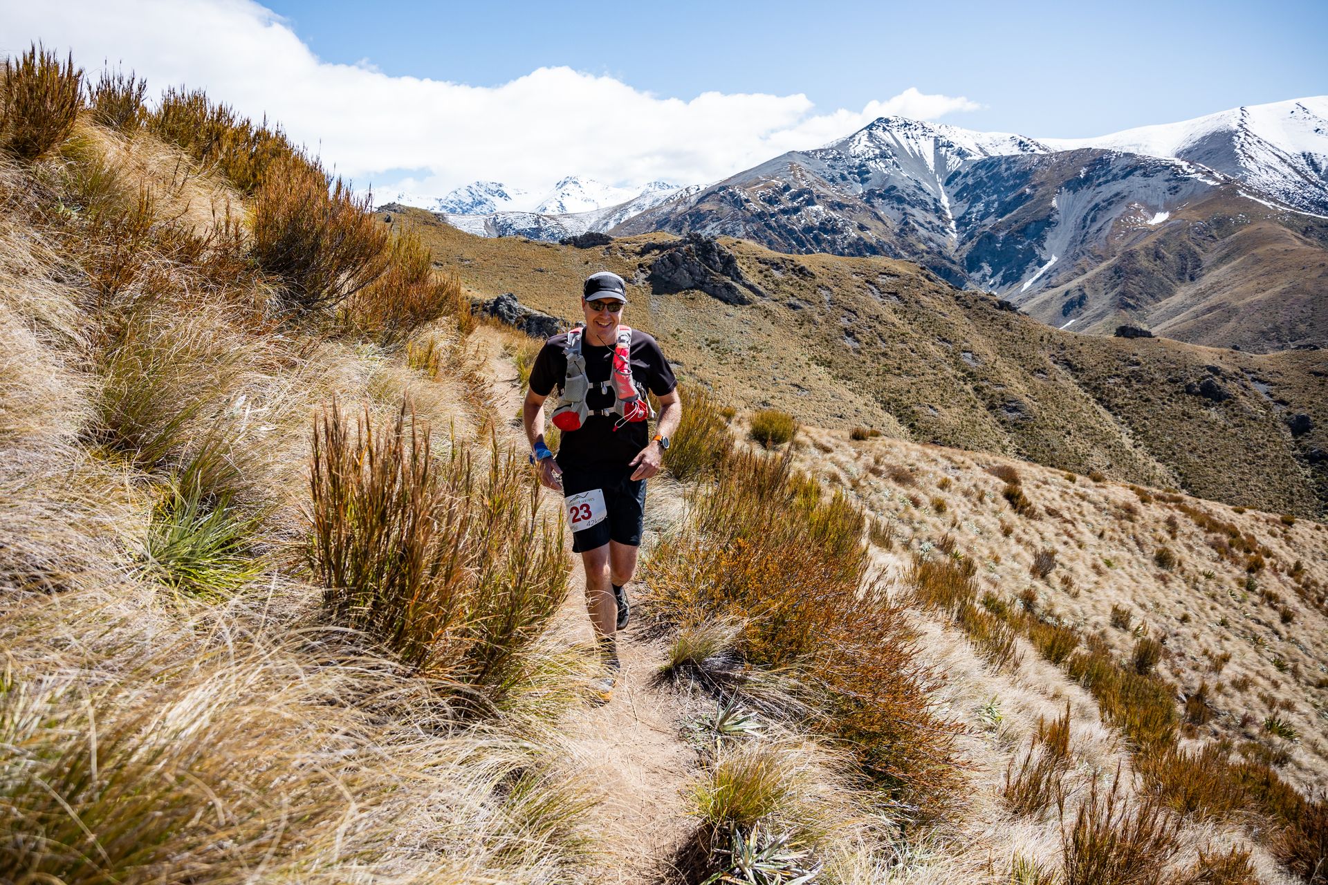 A man is running on a trail in the mountains.
