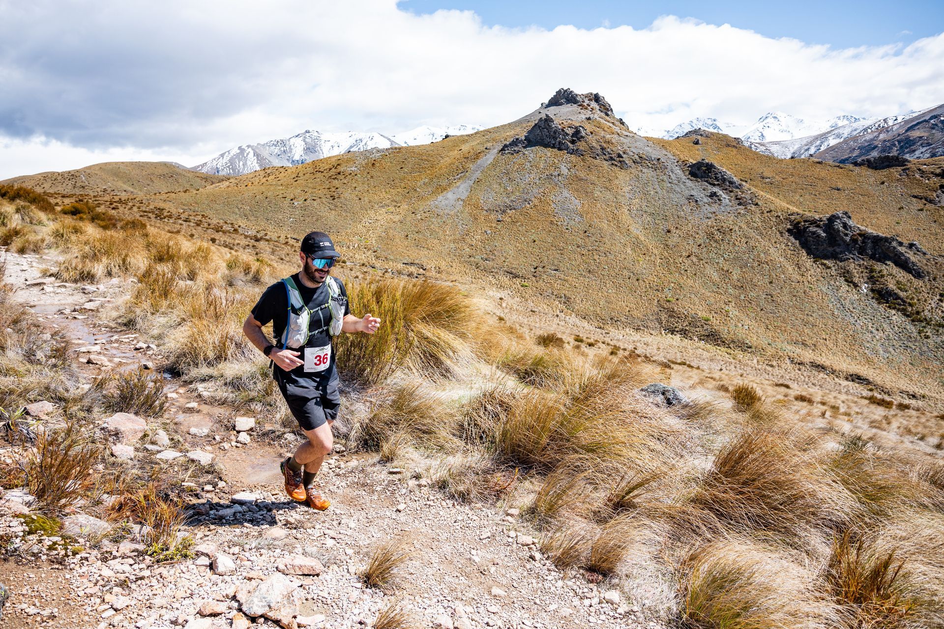 A man is running on a trail in the mountains.
