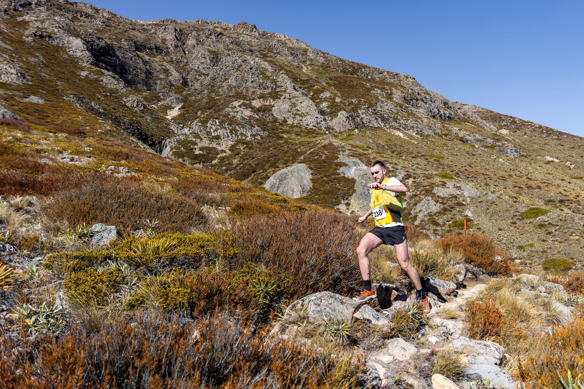 A man is running on a trail in the mountains.