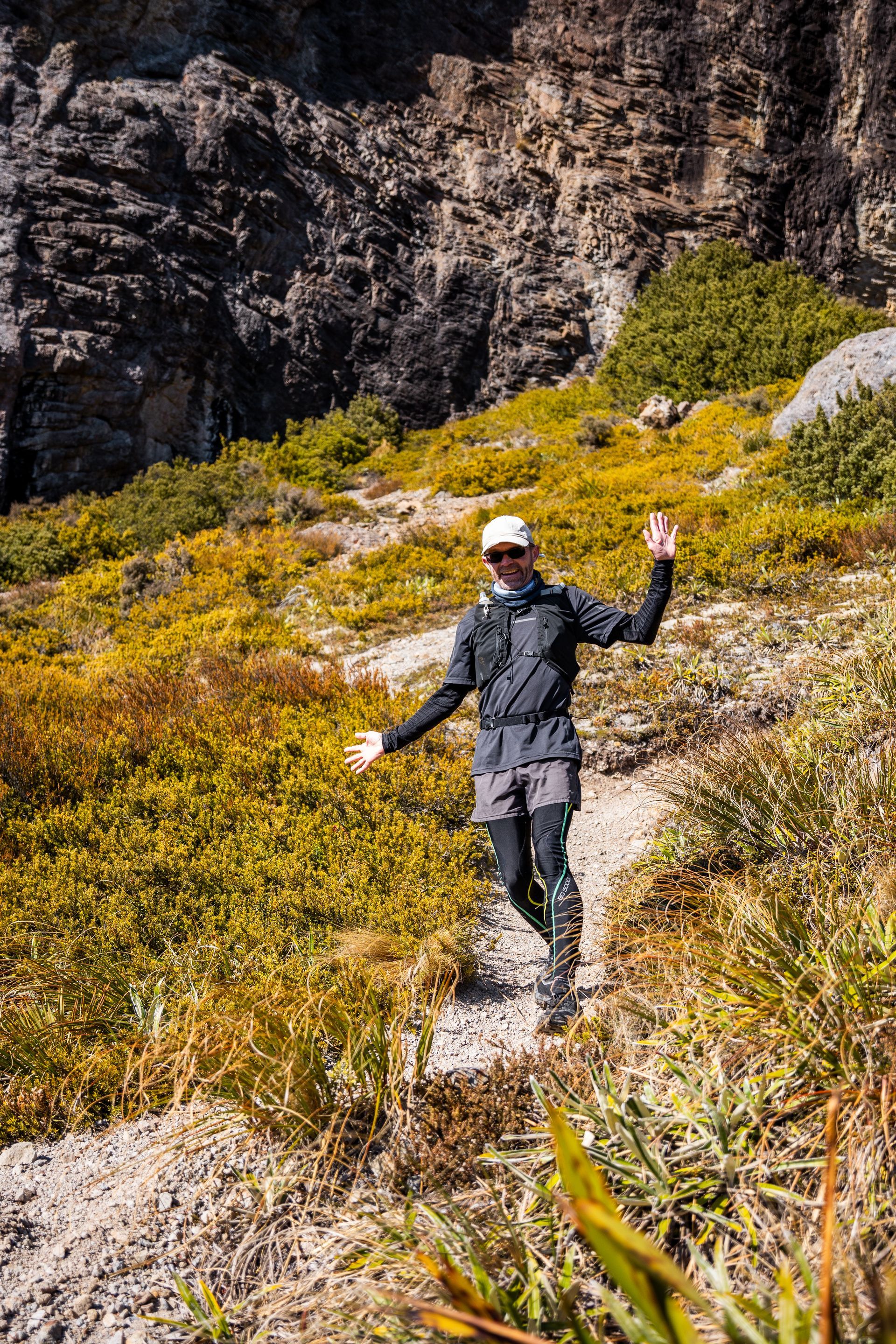 A man is walking down a dirt path in the mountains.