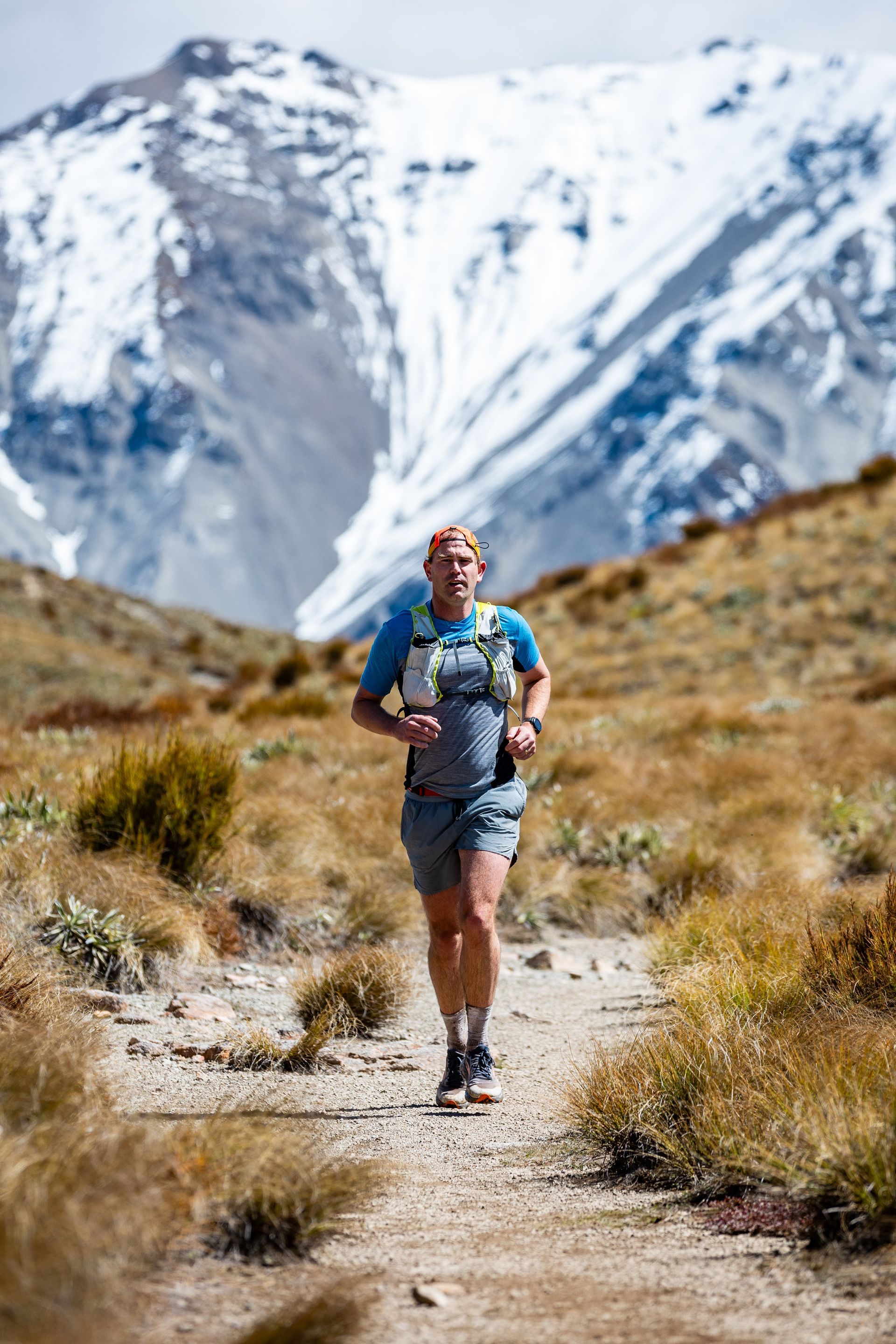 A man is running on a dirt path in the mountains.