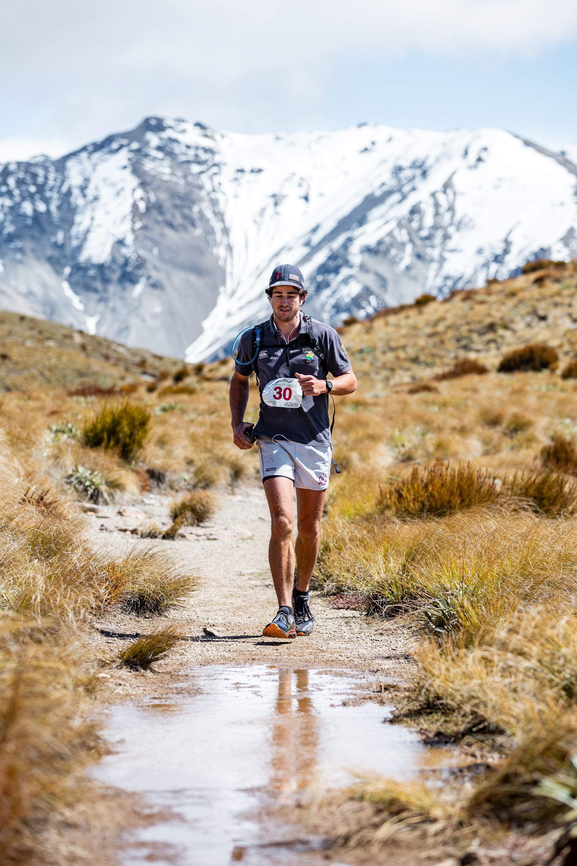 A man is running on a trail in the mountains.