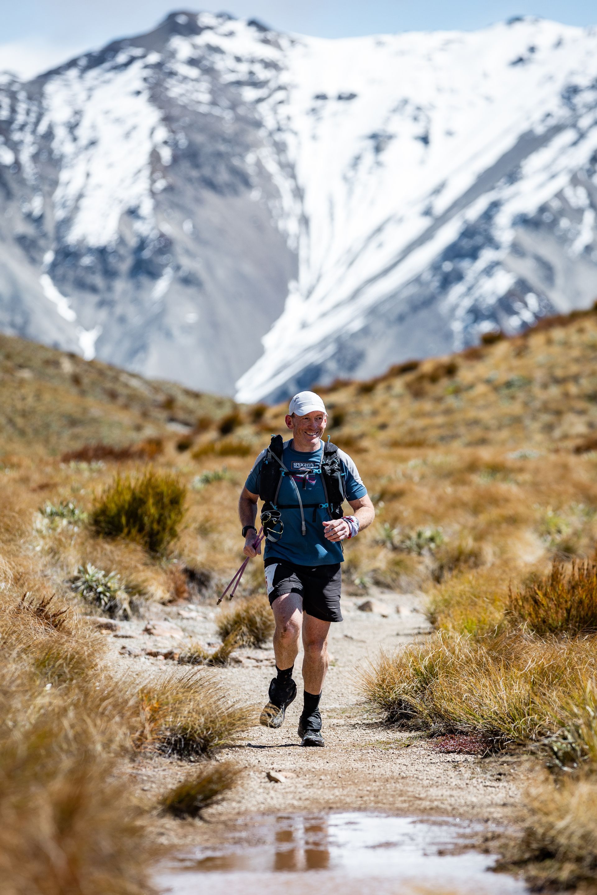A man is running on a trail in the mountains.