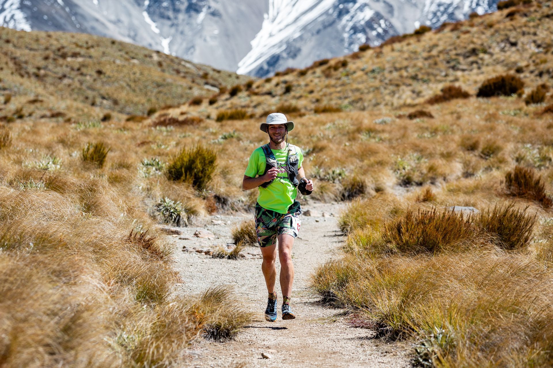 A man is walking down a dirt path in the mountains.