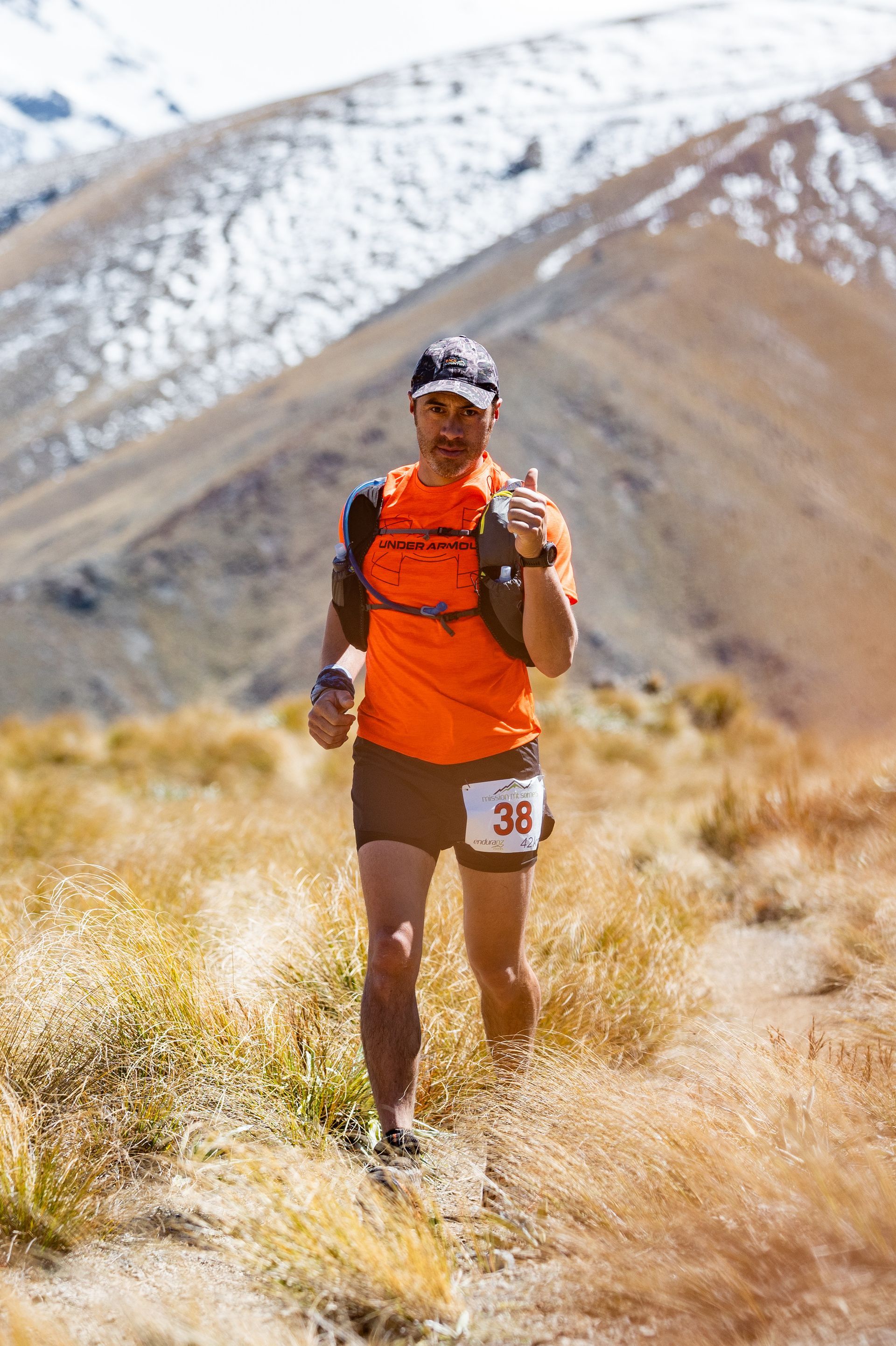 A man in an orange shirt is running up a hill.