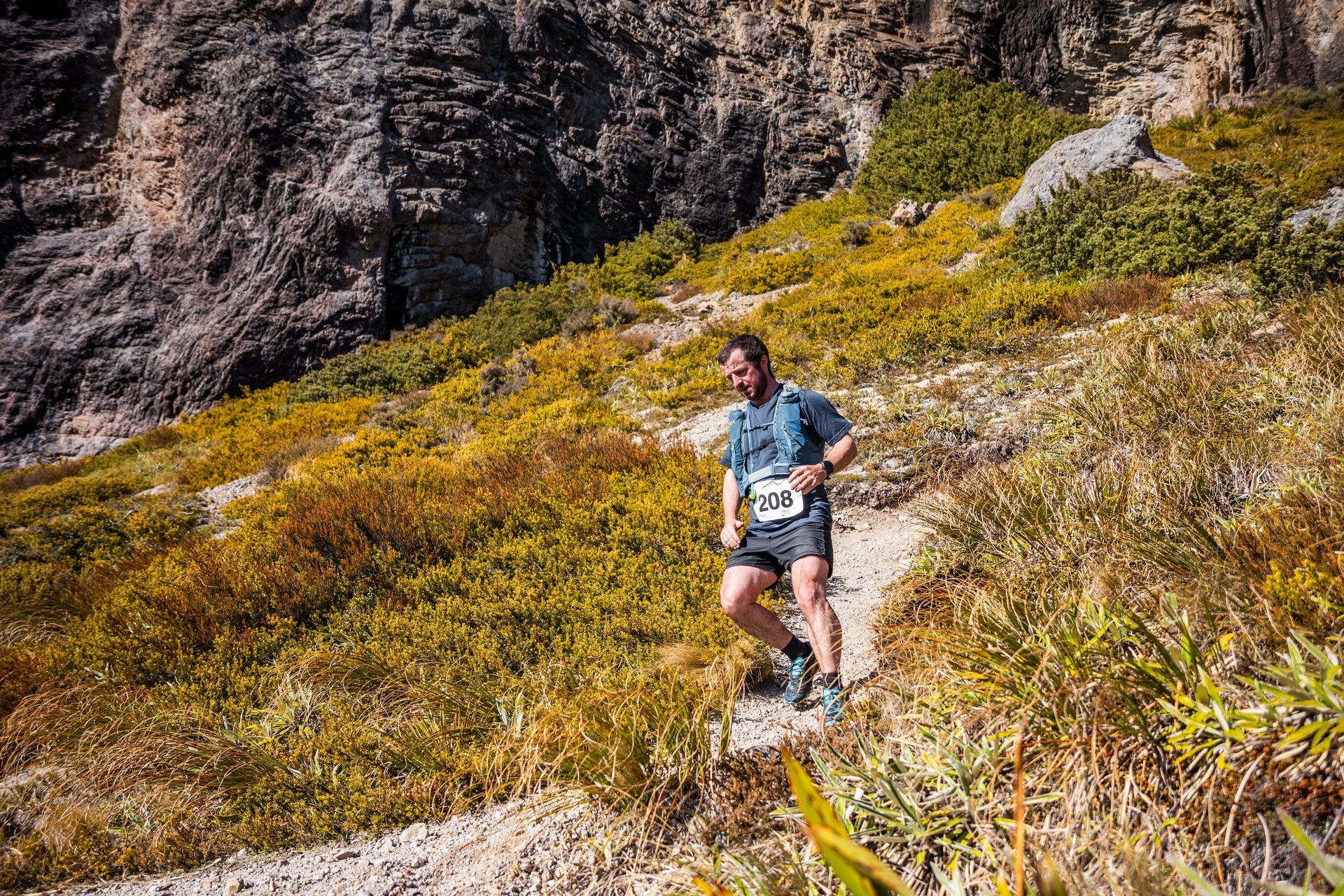 A man is running up a hill on a trail.
