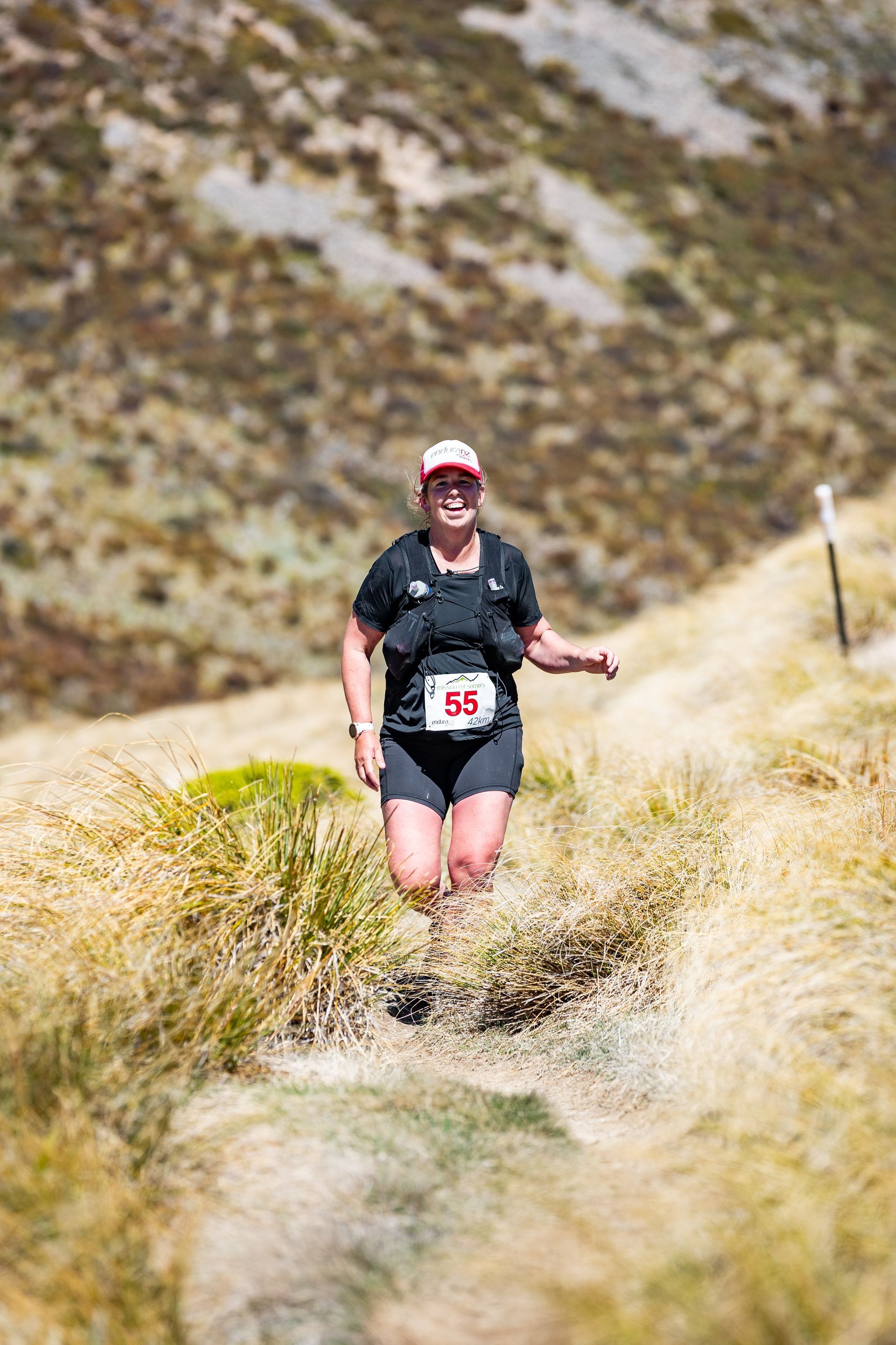 A woman is running on a trail in the mountains.