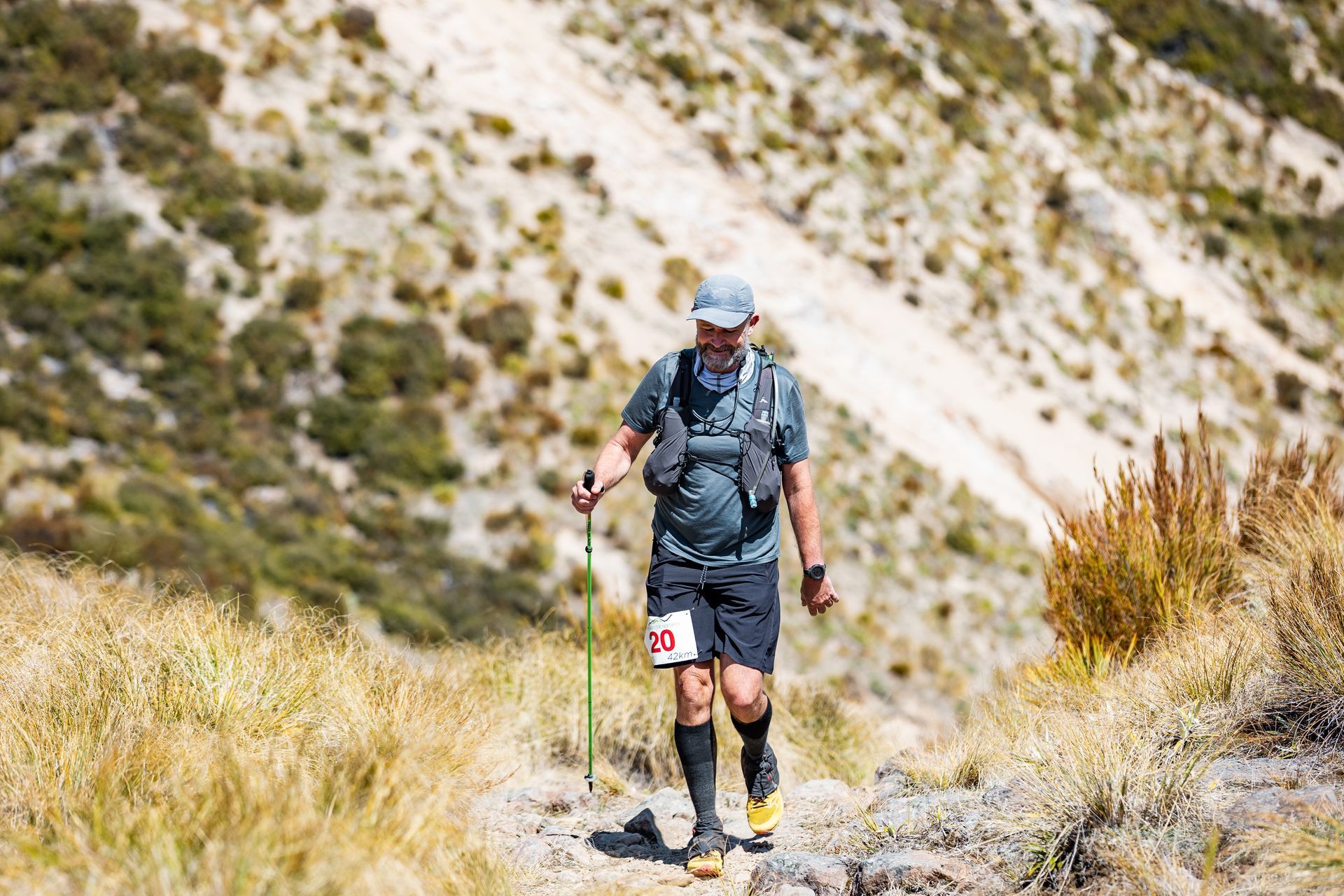 A man is walking up a hill with hiking poles.