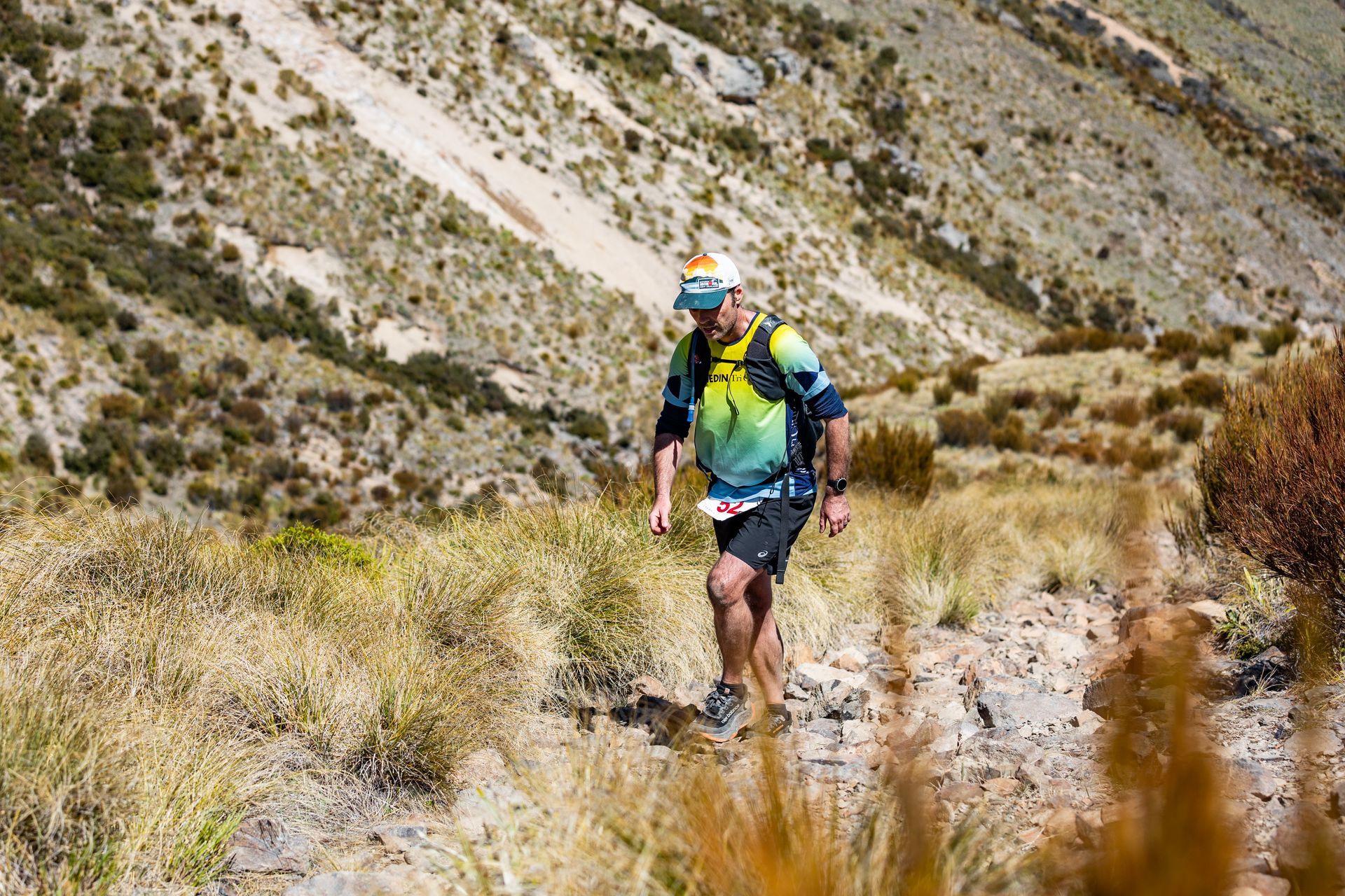 A man is hiking up a hill in the mountains.