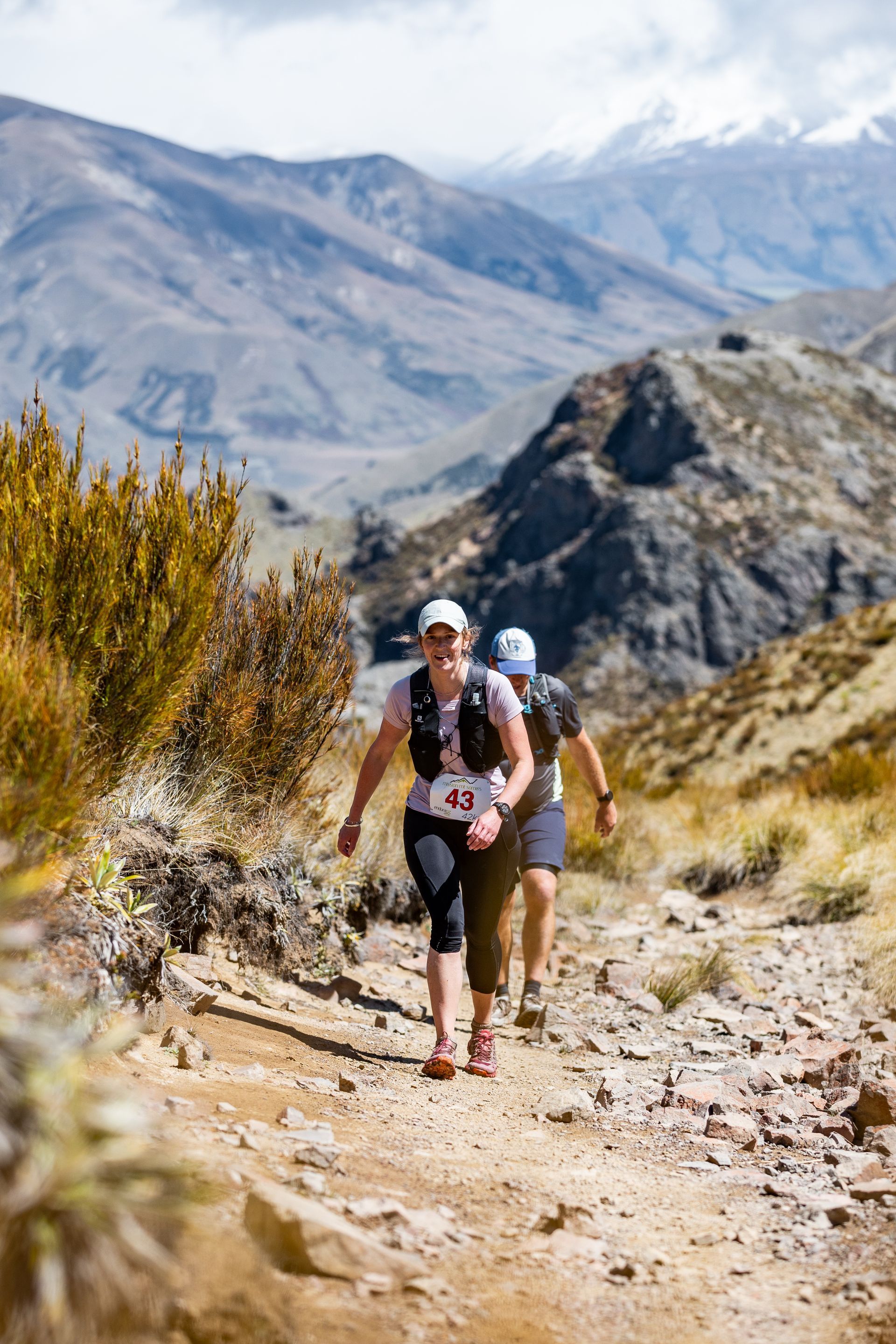 A group of people are running down a trail in the mountains.