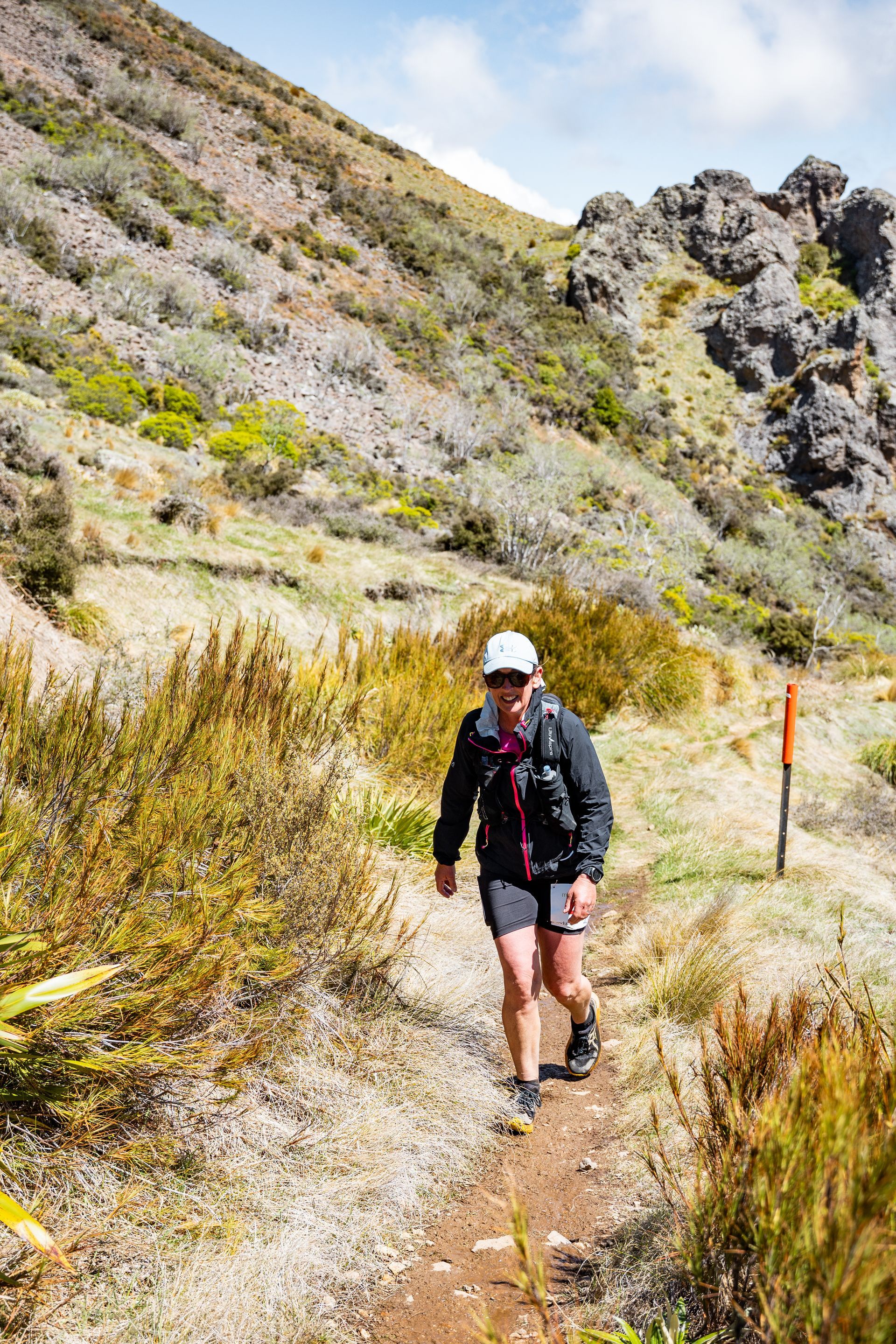 A woman is walking down a dirt path in the mountains.