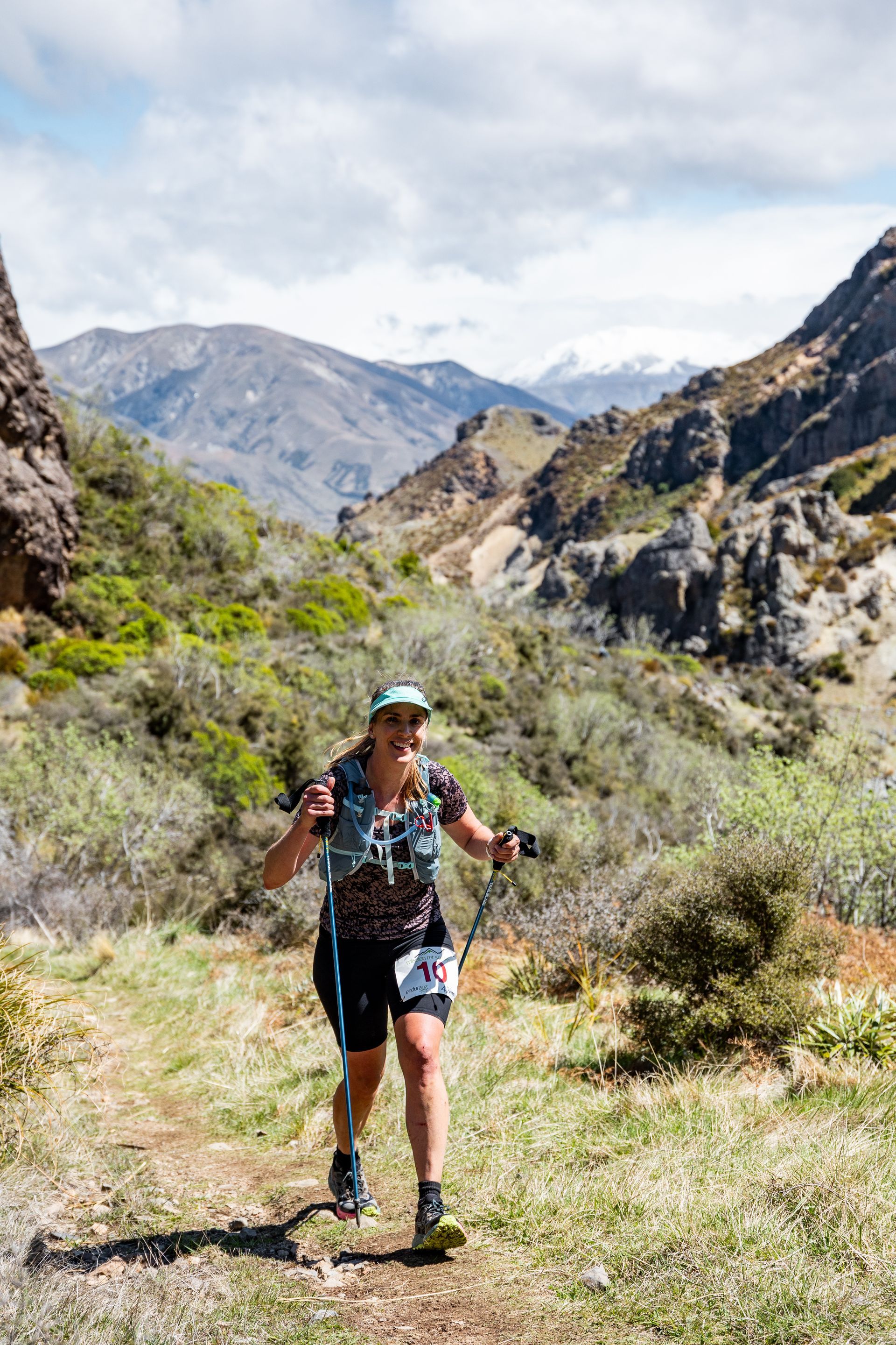 A woman is running on a trail in the mountains.