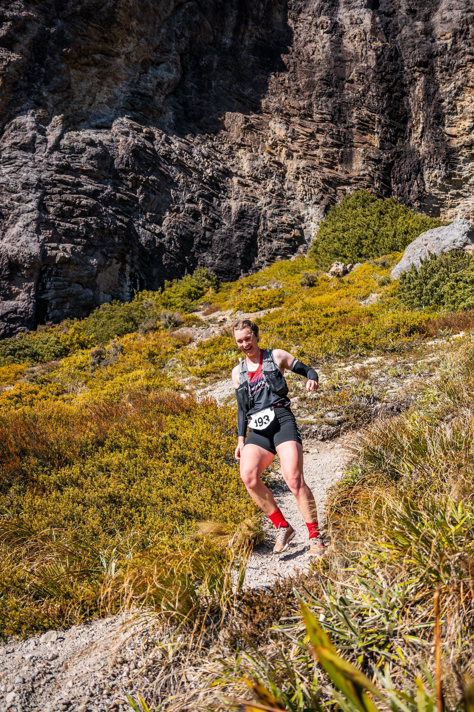 A man is running down a trail in the mountains.